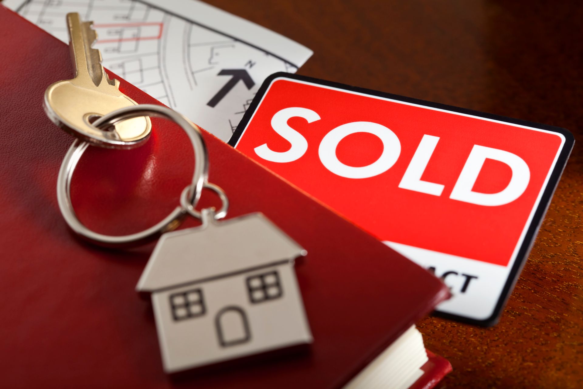 Conveyancing concept with house keys, red book, and sold card representing property transfer.