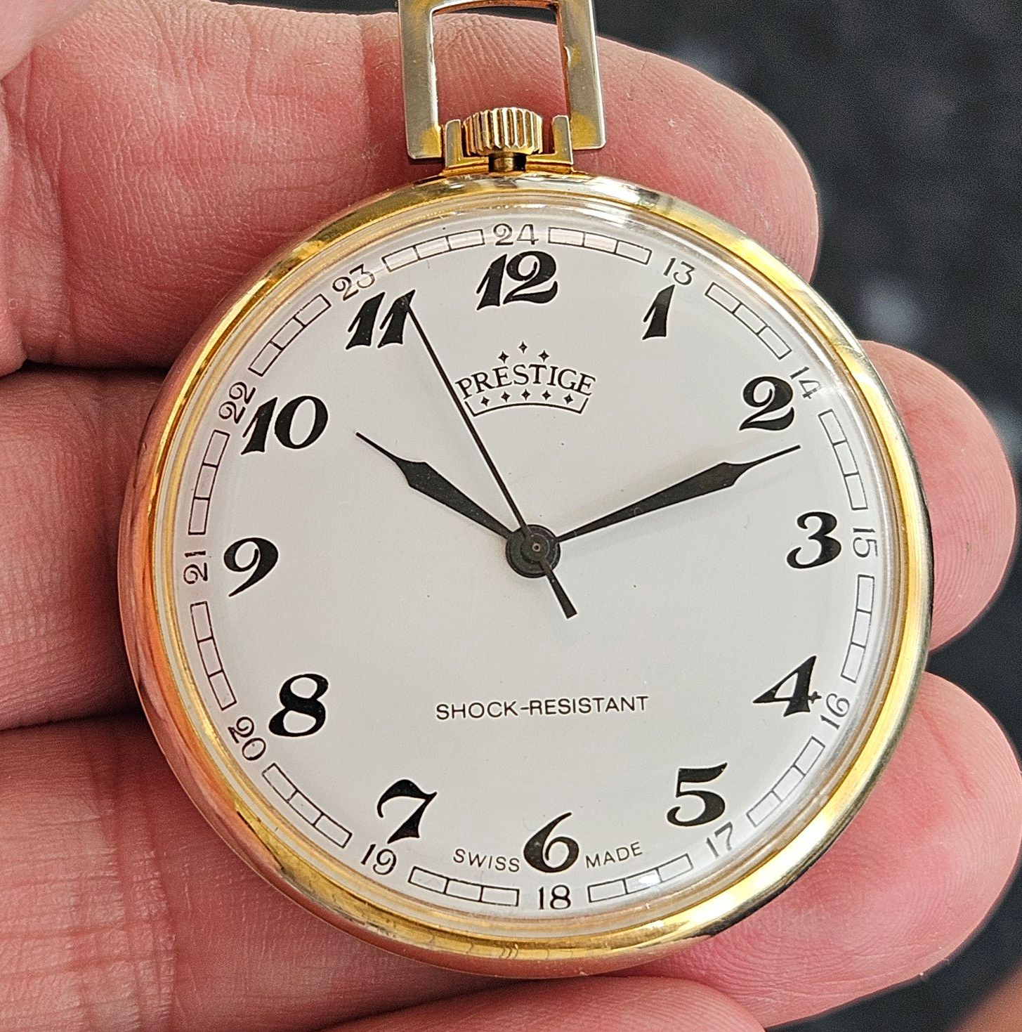 Gold Prestige pocket watch with white face, black numbers, and black hands. 