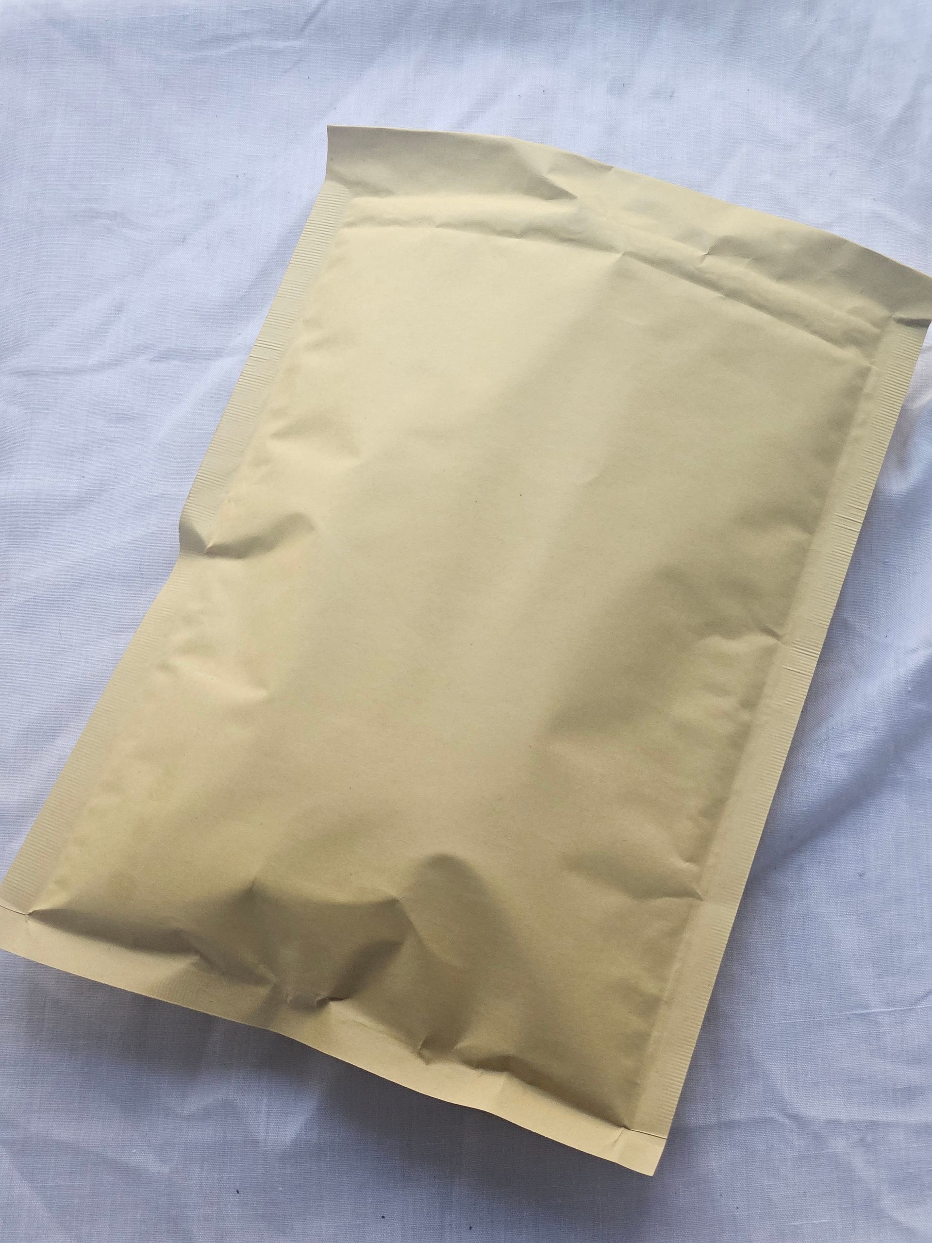 Tan padded envelope on a wrinkled white sheet.