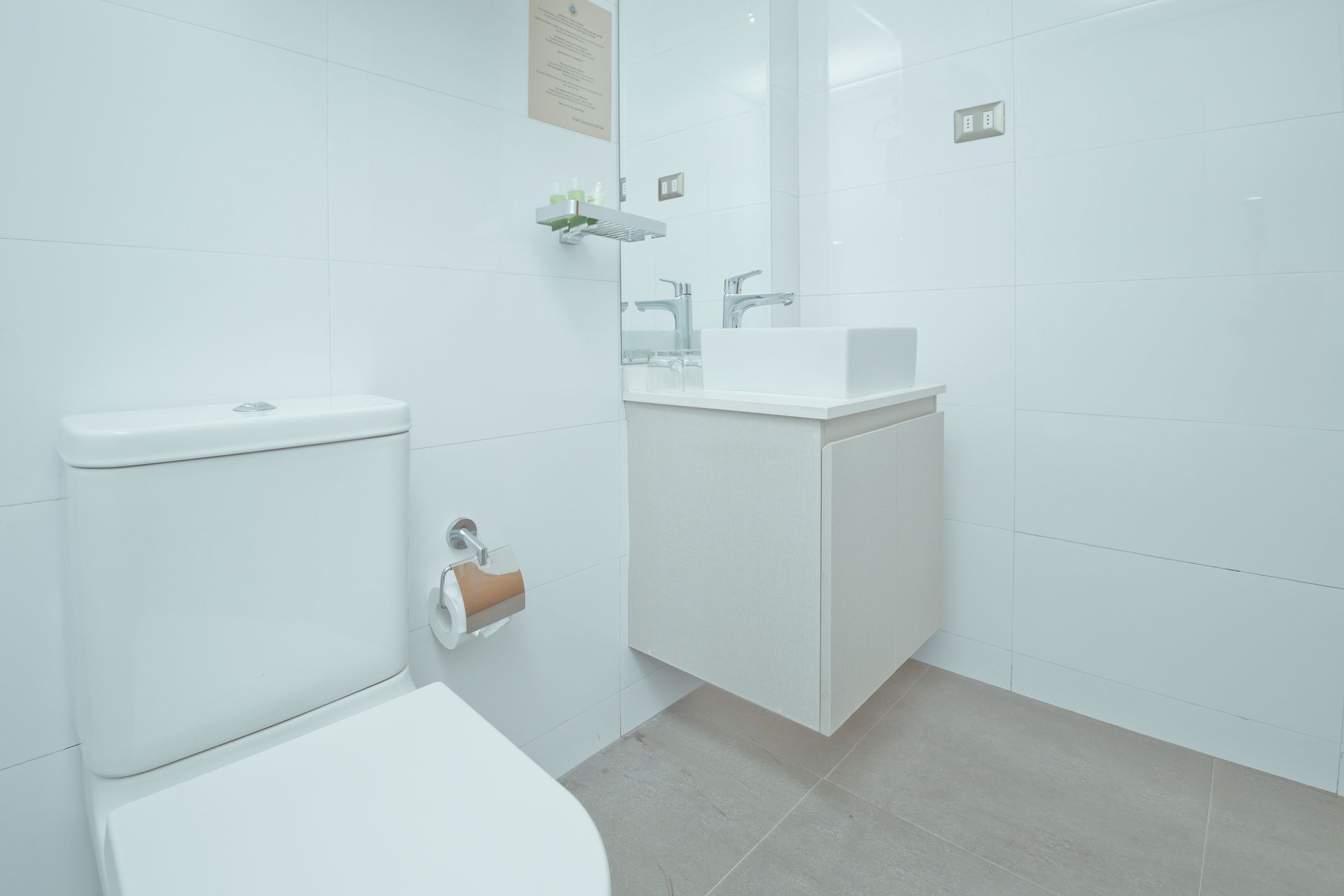 A bathroom with a toilet , sink and mirror.