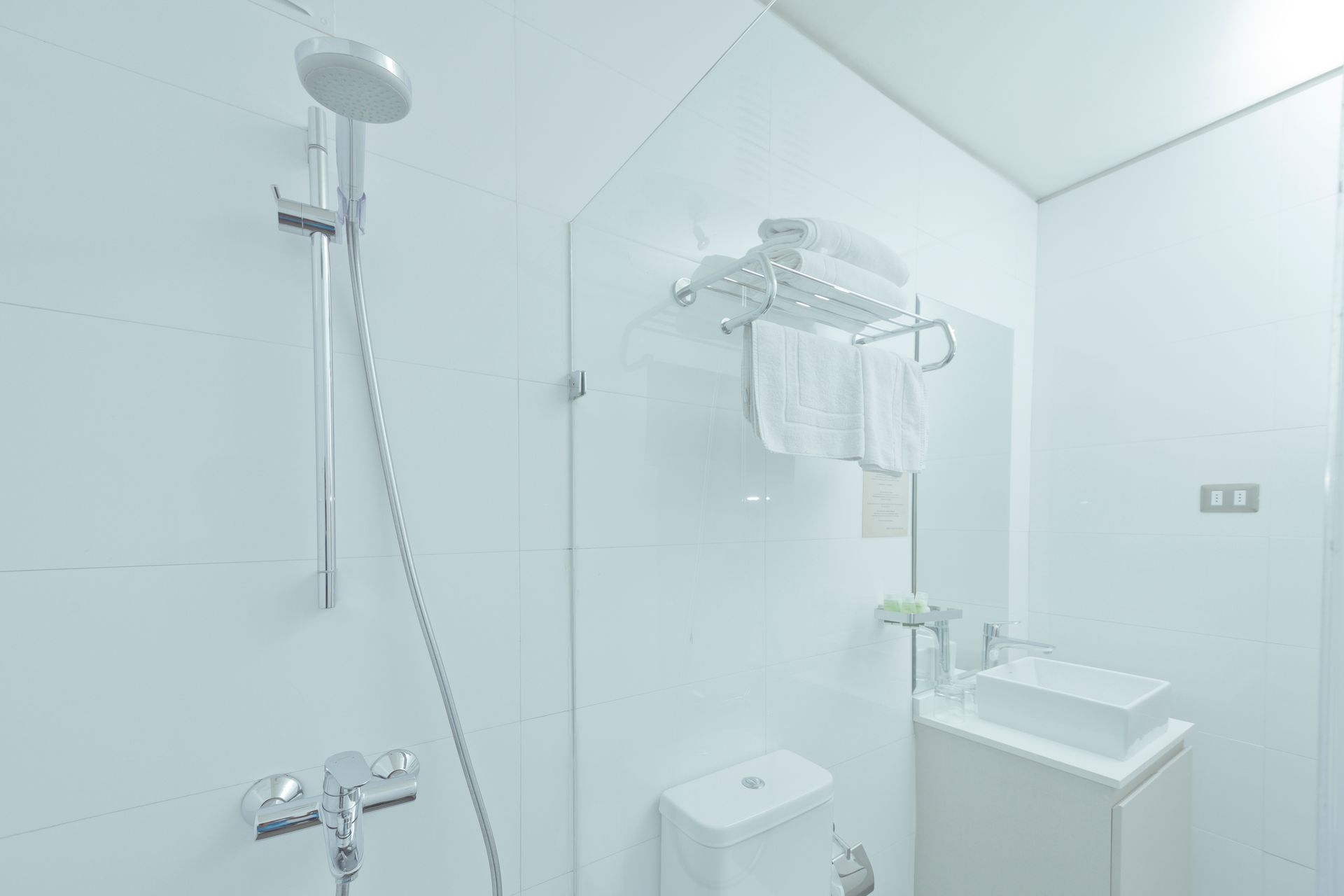 White bathroom with shower, toilet, sink, and towel rack.