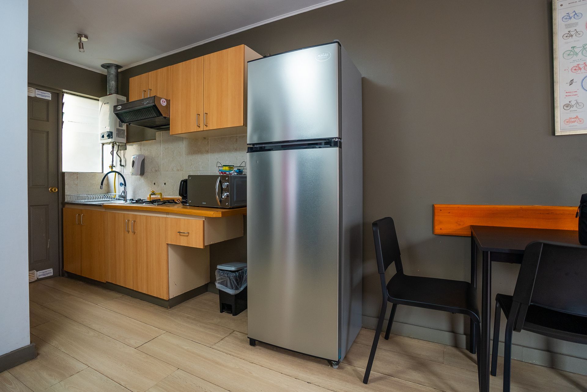 A kitchen with a stainless steel refrigerator and a table and chairs.