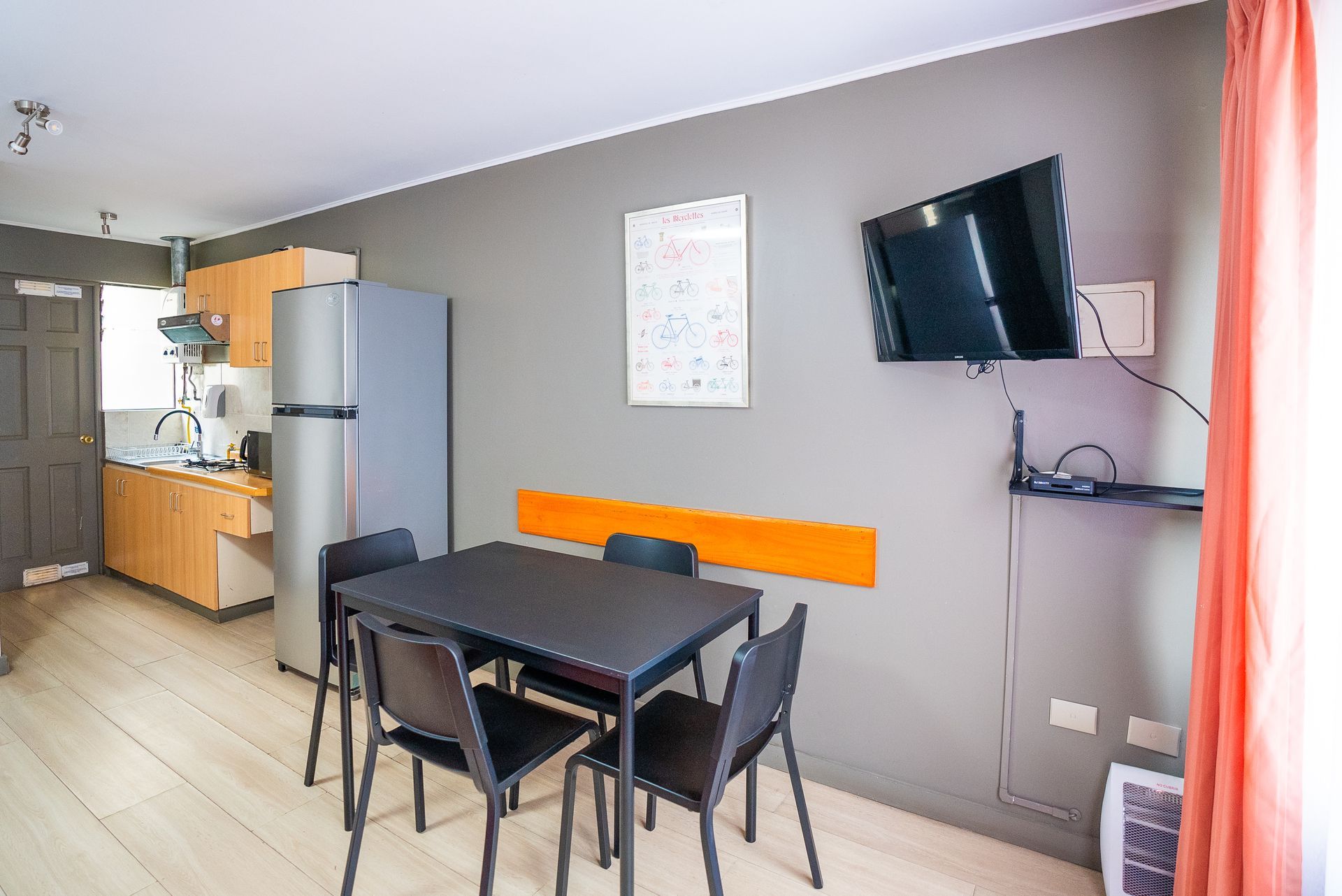 Small apartment dining area with a table, chairs, kitchen, fridge, and wall-mounted TV