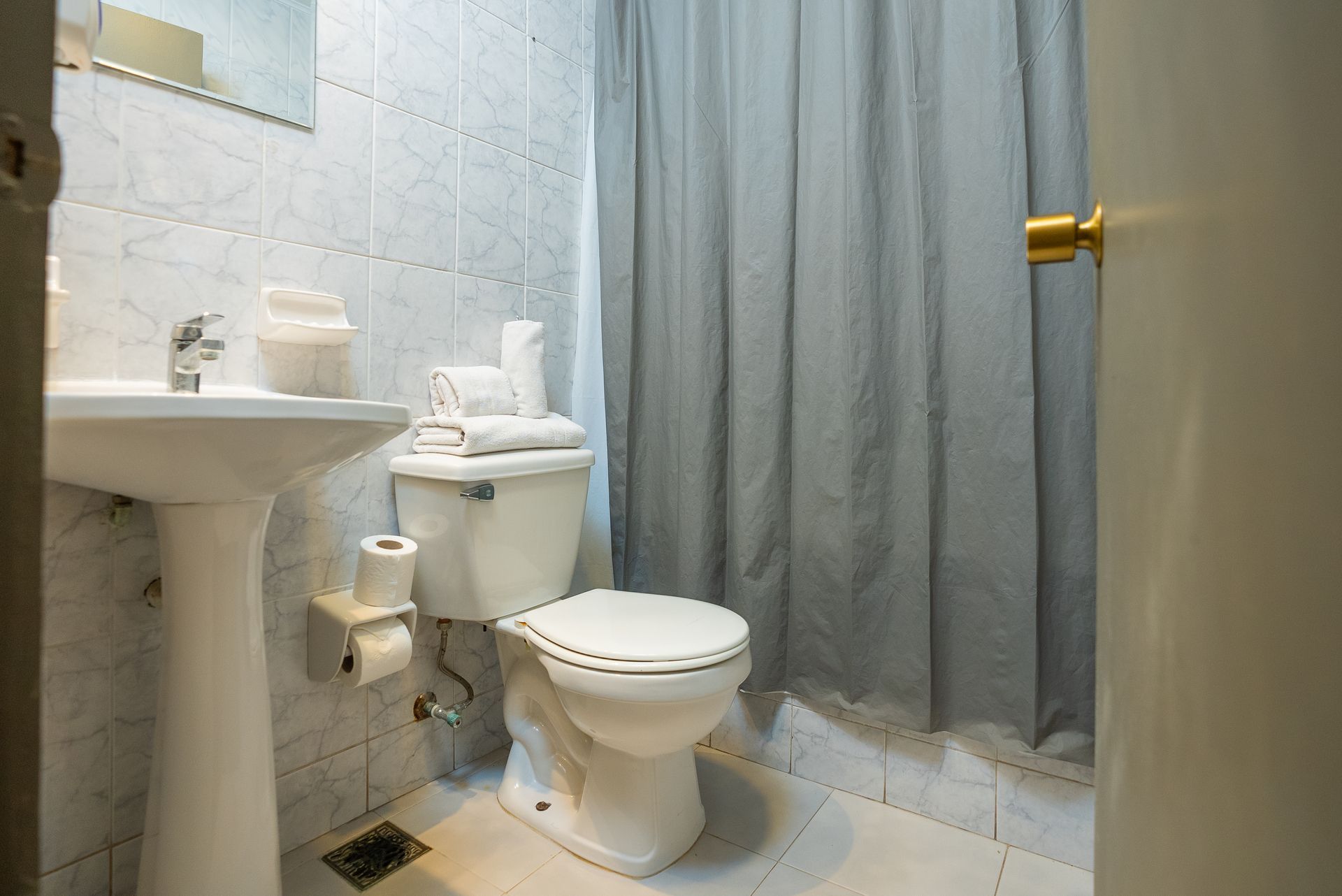 A bathroom with a toilet , sink , and shower curtain.