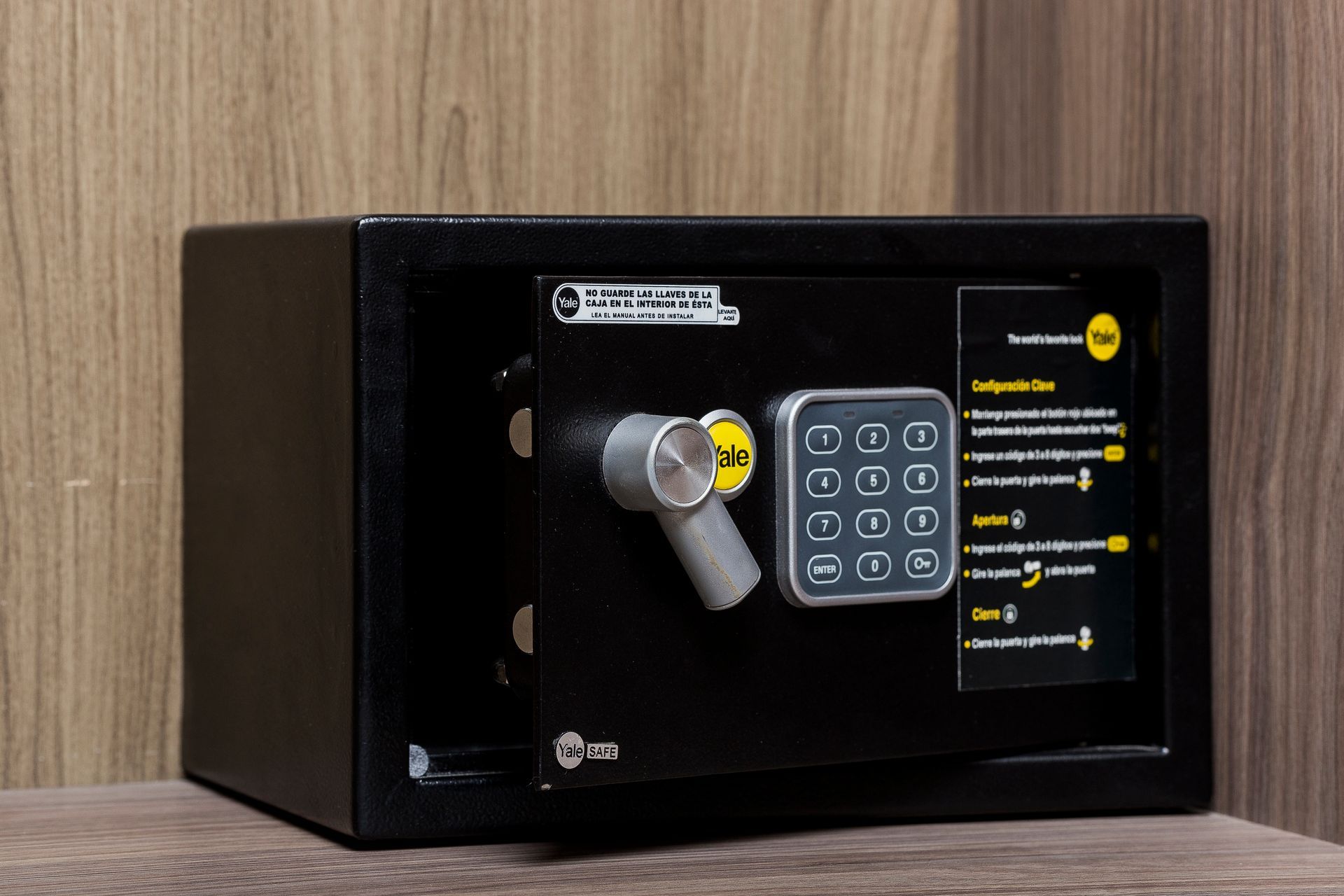 A black safe with a digital lock is sitting on a wooden table.