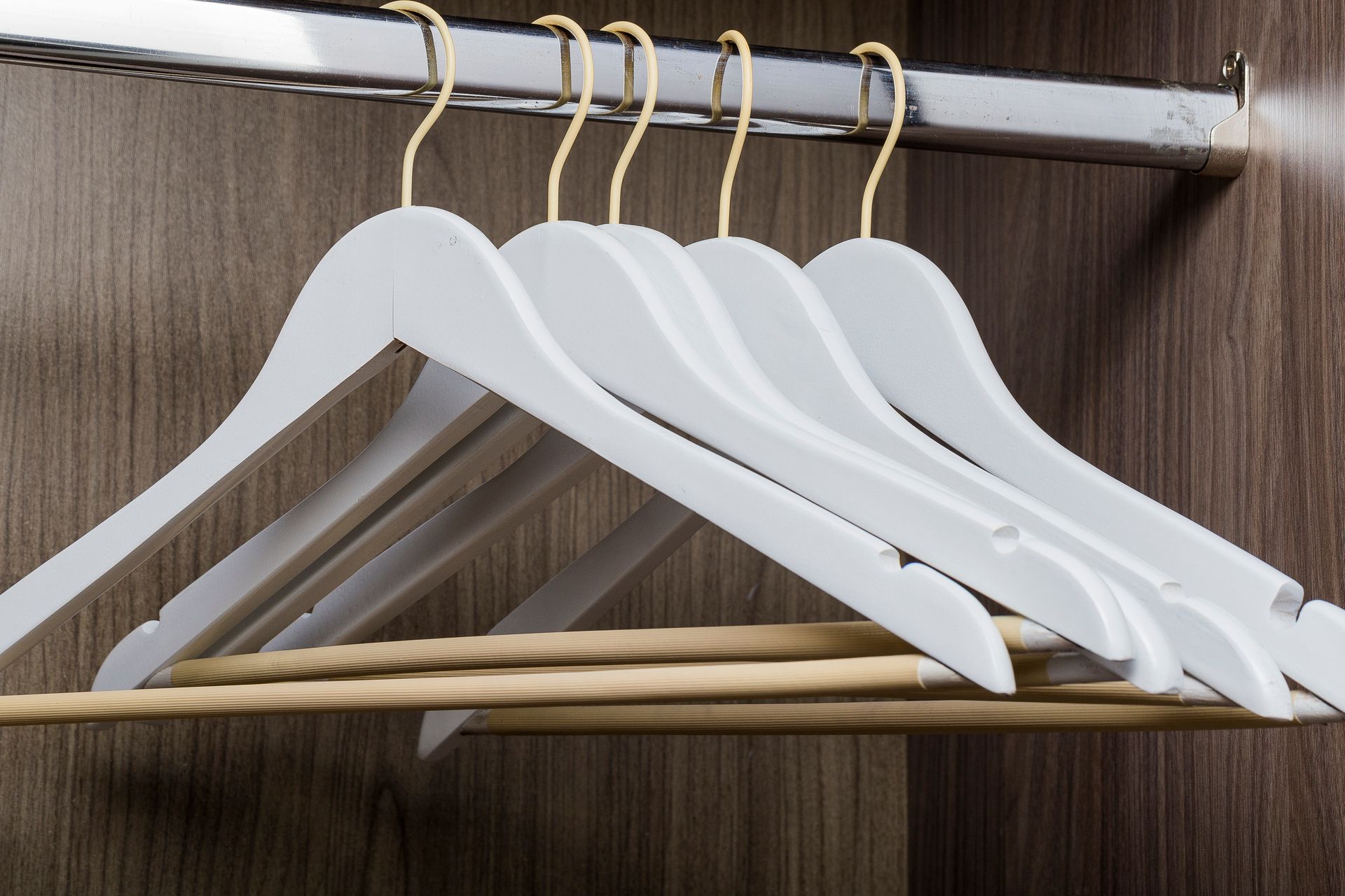 A row of white hangers hanging in a closet