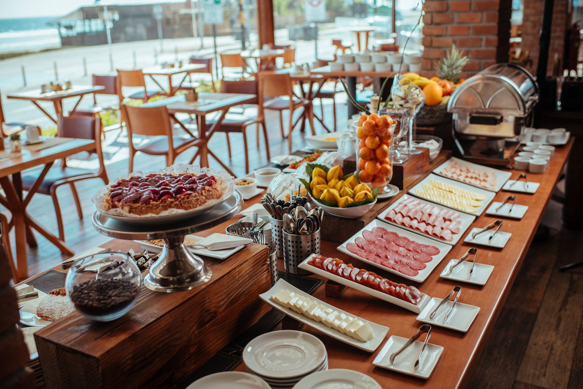 Buffet table set with various foods, including cake, fruits, and meats; a restaurant setting.