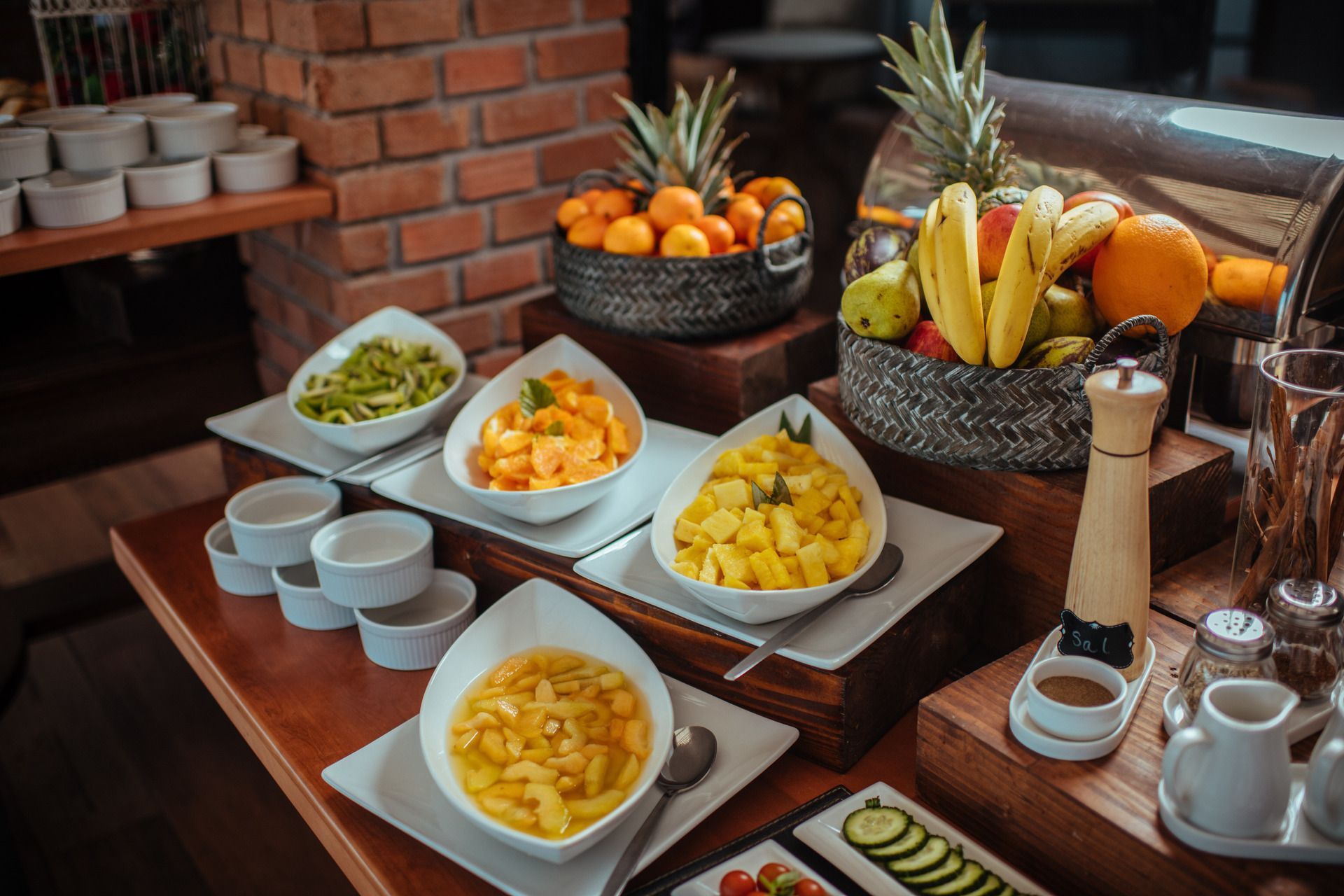 A buffet table with bowls of food and fruit on it.