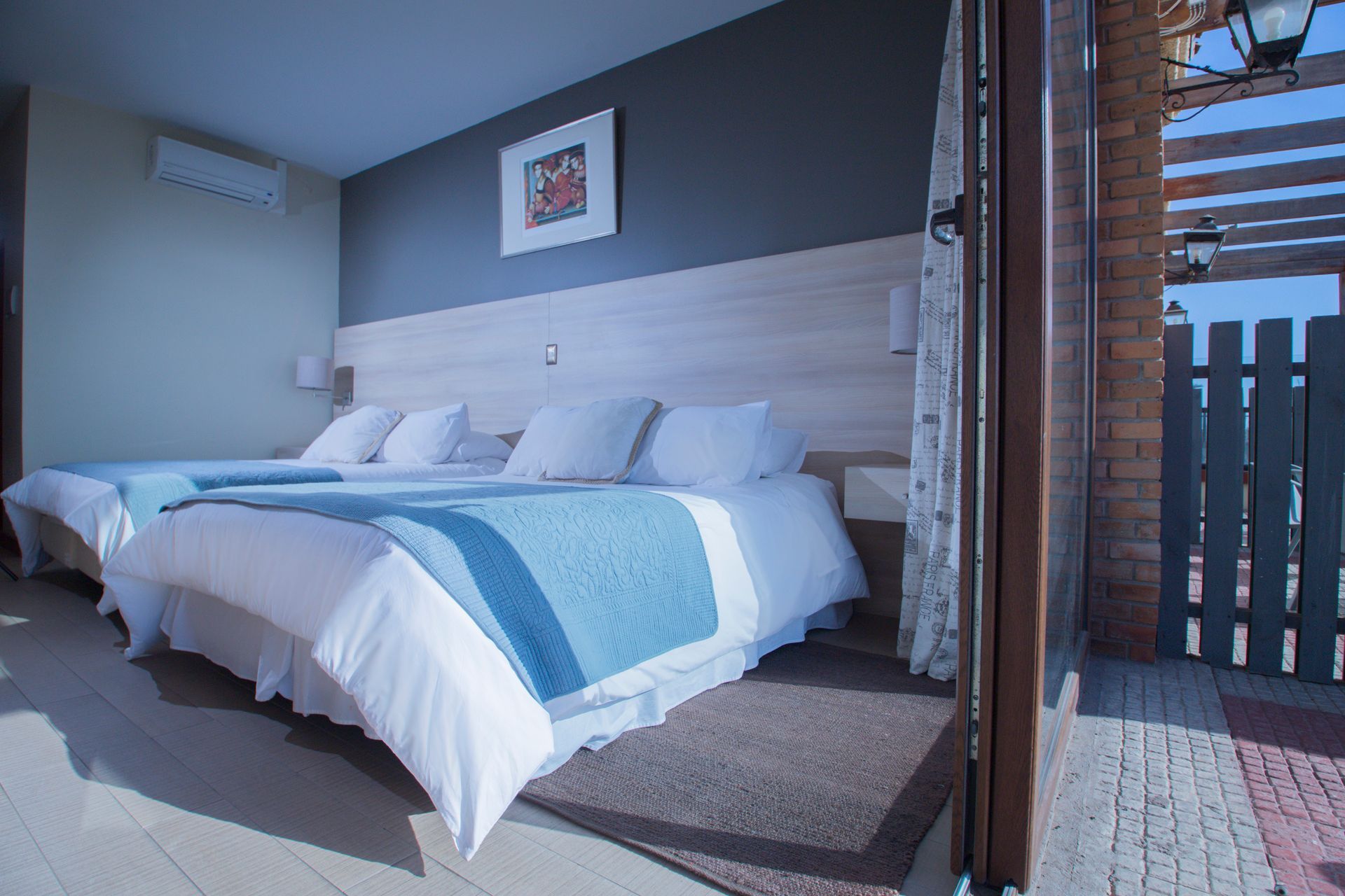 A hotel room with two beds and a balcony.