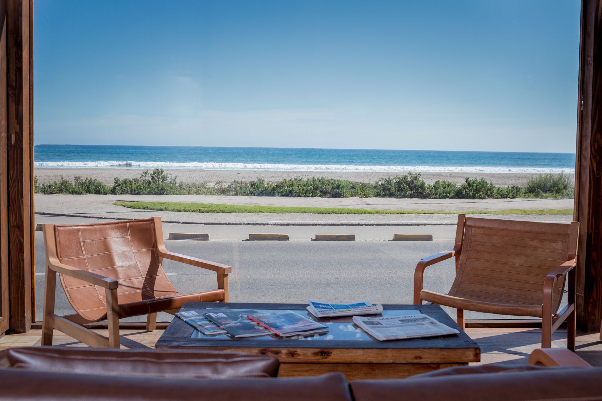 Patio chairs facing a beach and ocean view through an open doorway