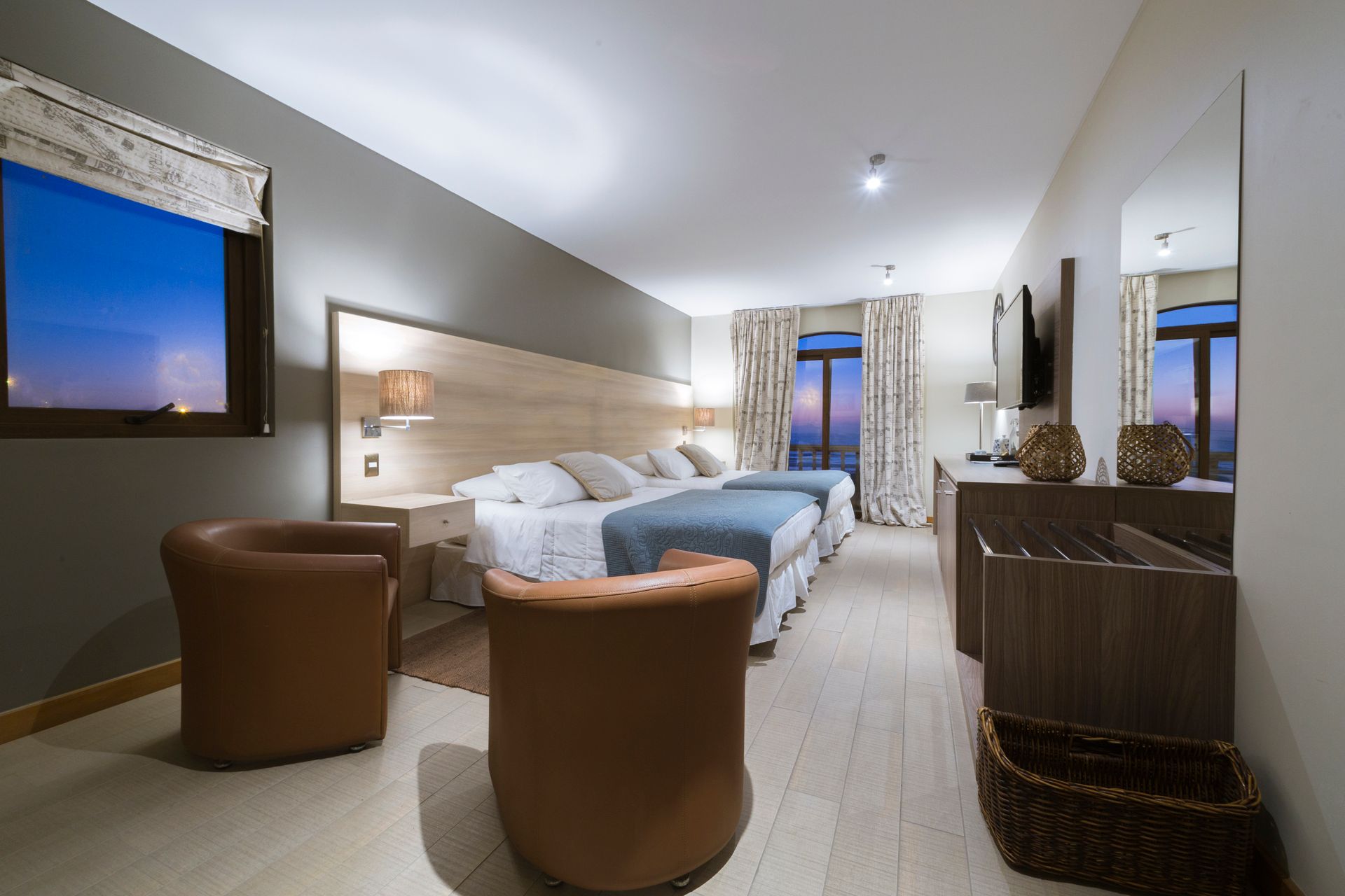 A hotel room with three beds and two chairs
