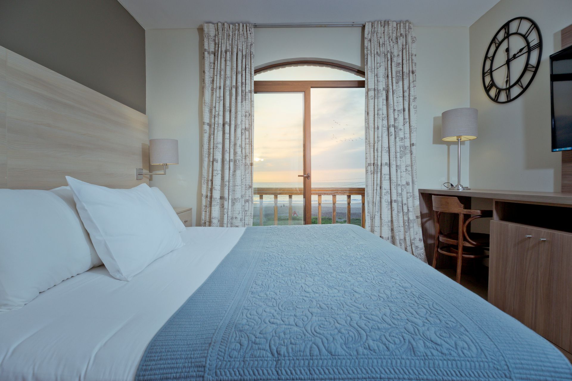 A hotel room with a king size bed and a large window.