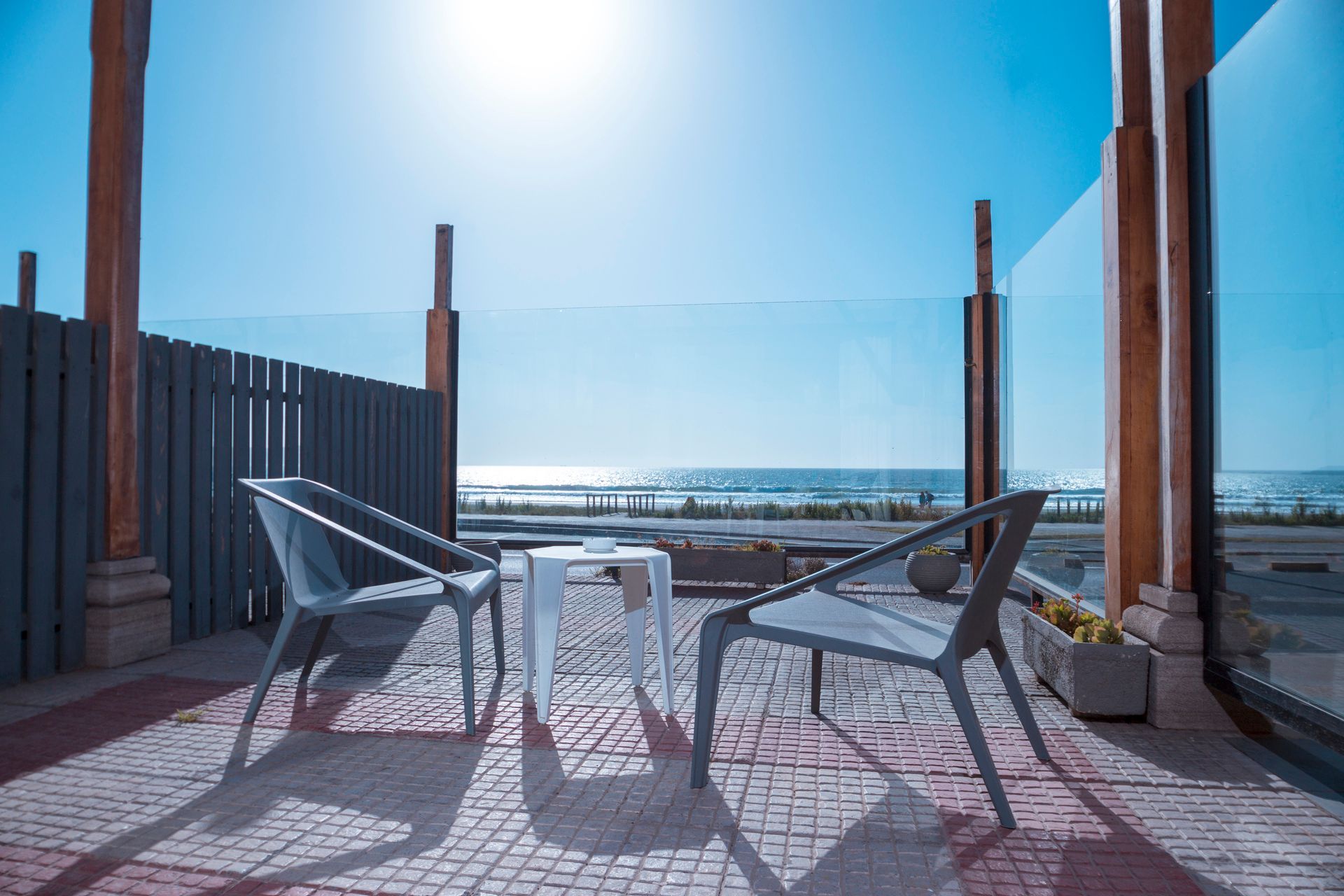 A balcony with a table and chairs overlooking the ocean.