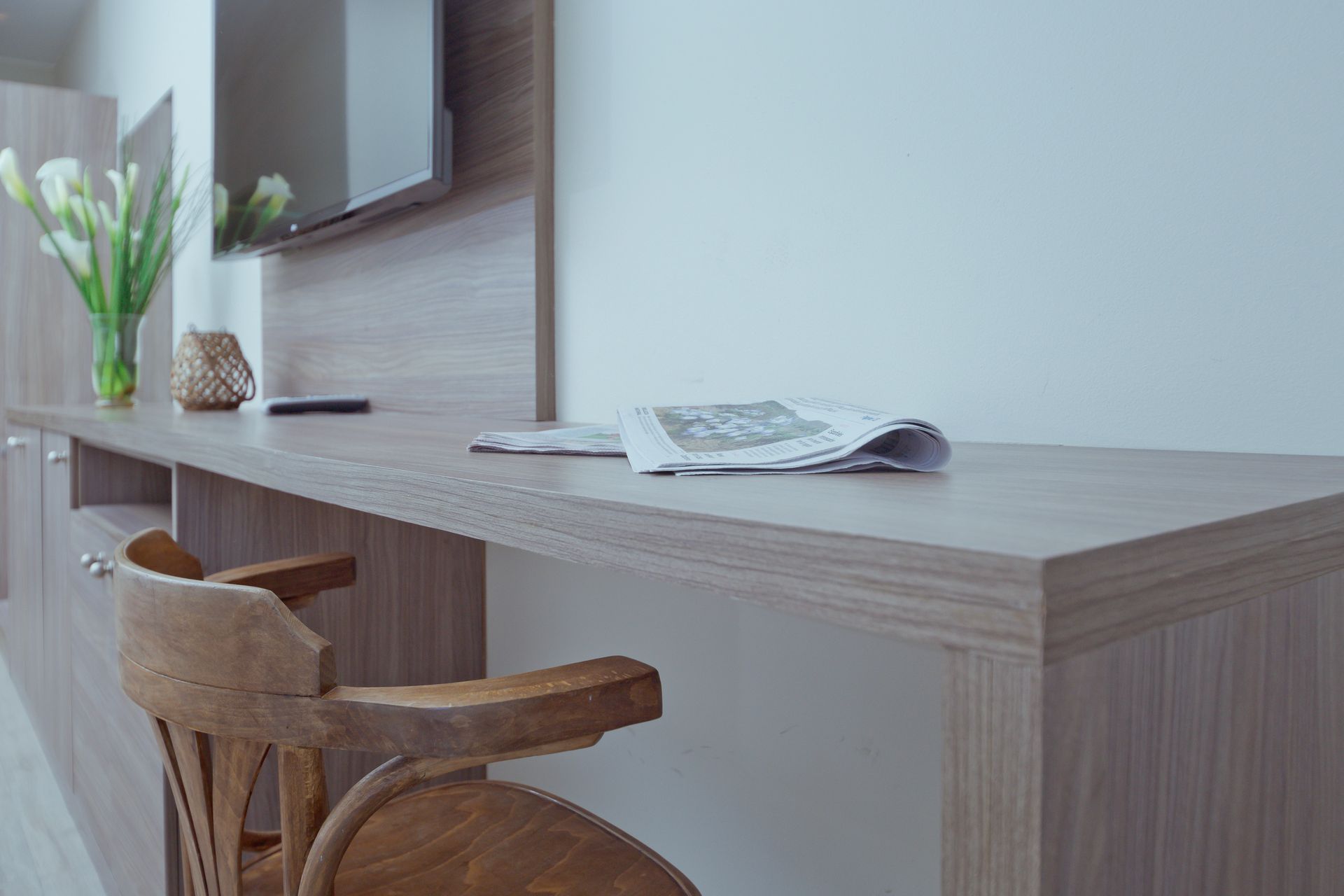 A wooden desk with a chair and a newspaper on it.