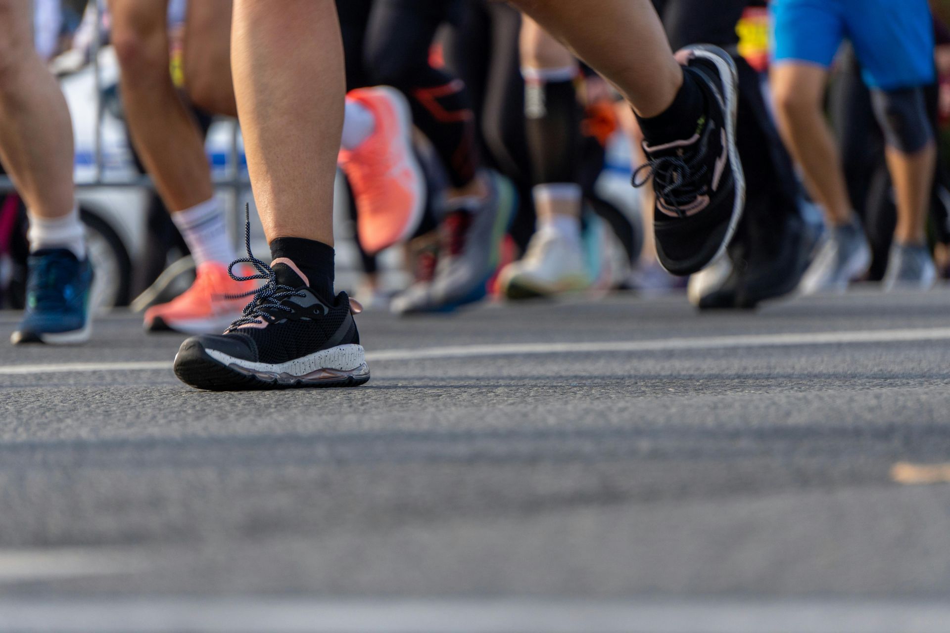 Runners’ feet in motion on a road during a race, with colorful sneakers and blurred legs in the background