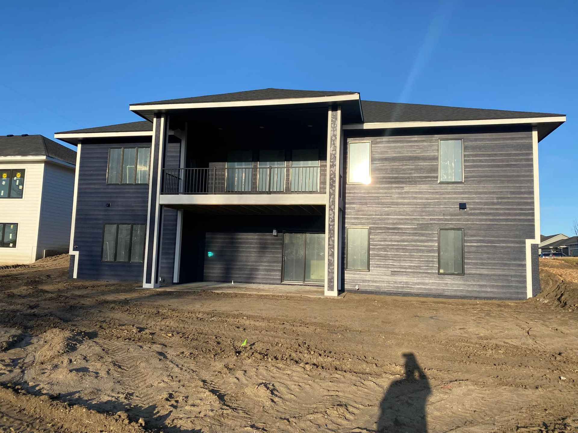 A large house with a lot of windows is sitting on top of a dirt field.
