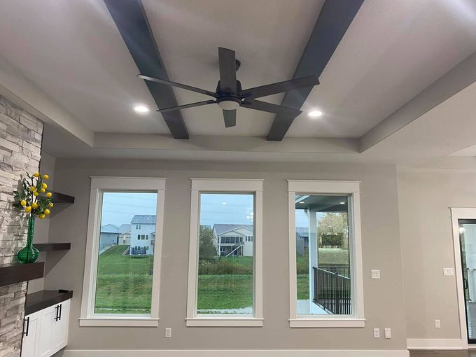 A living room with three windows and a ceiling fan.