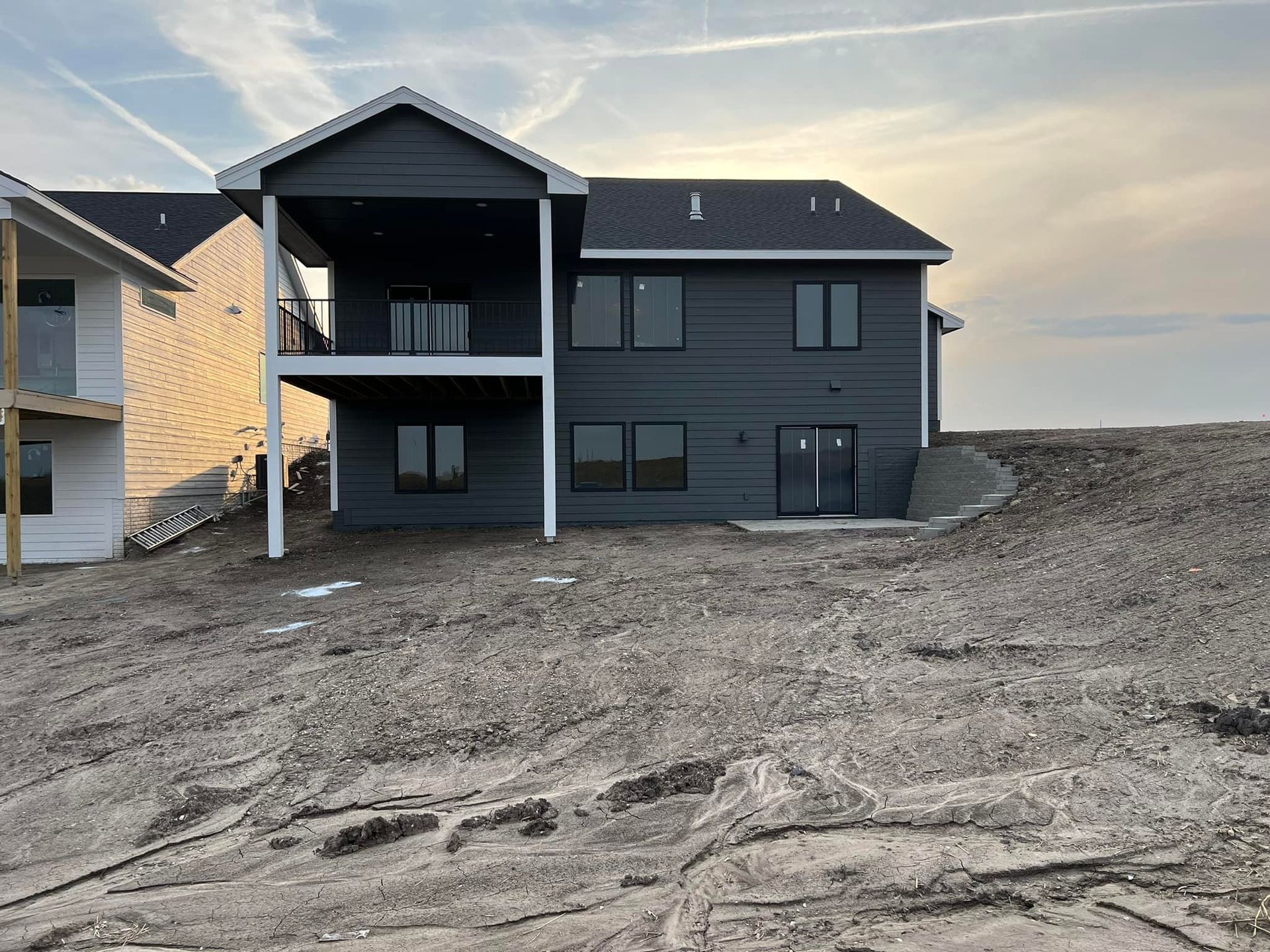 A large house is sitting on top of a dirt hill.