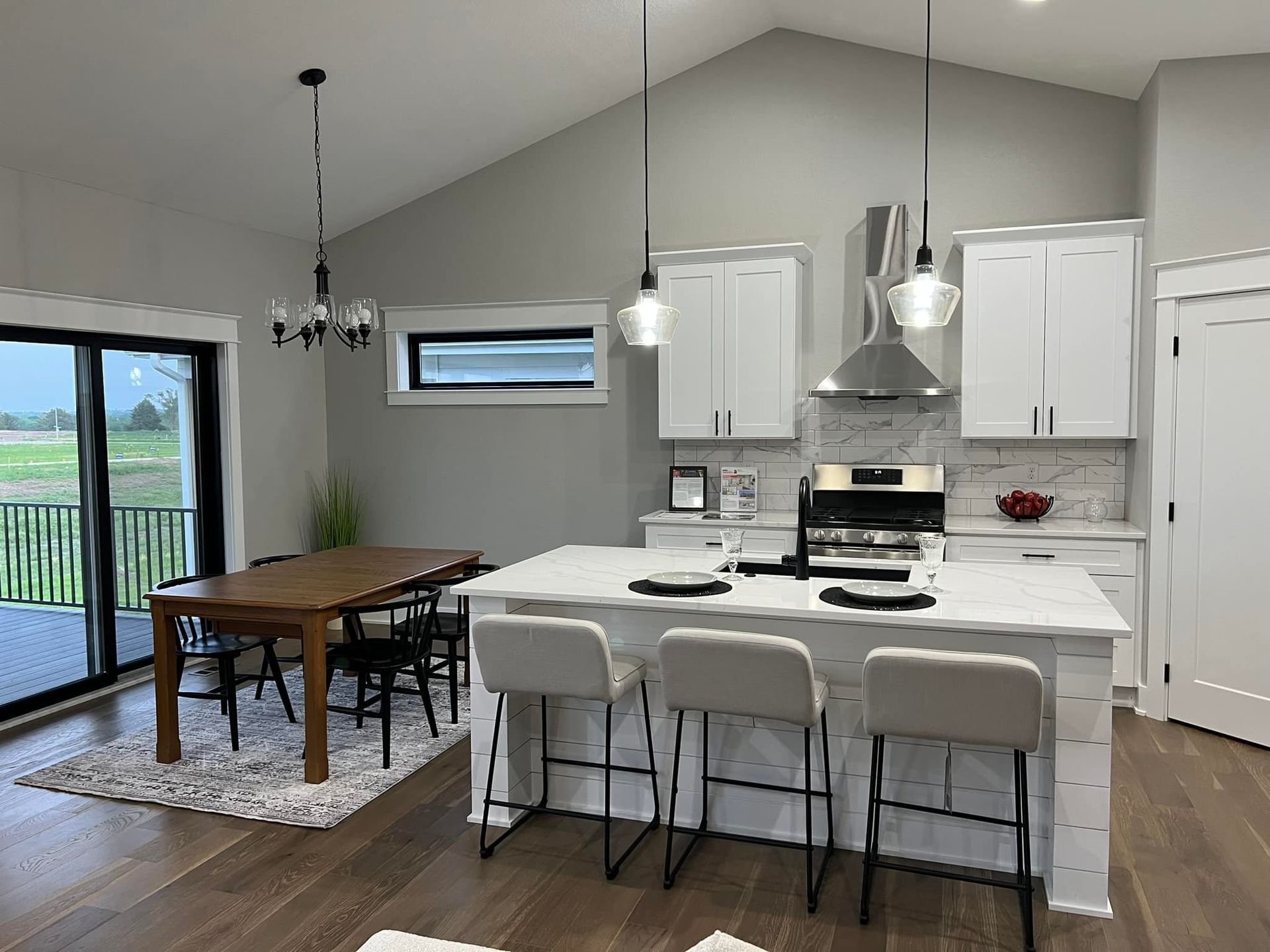 A kitchen with white cabinets , a large island , a table and chairs.