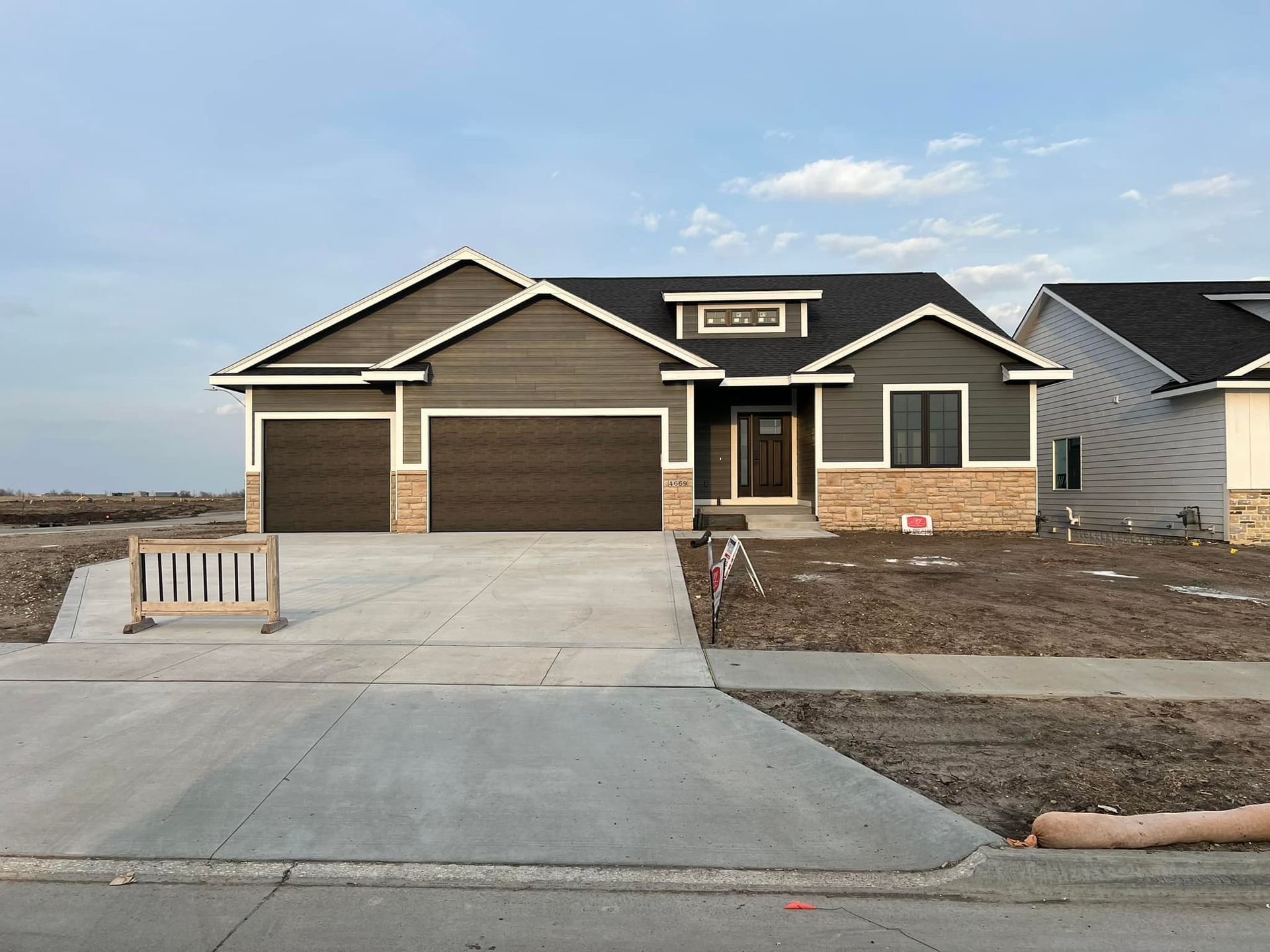 A house is being built in a residential area with a concrete driveway.