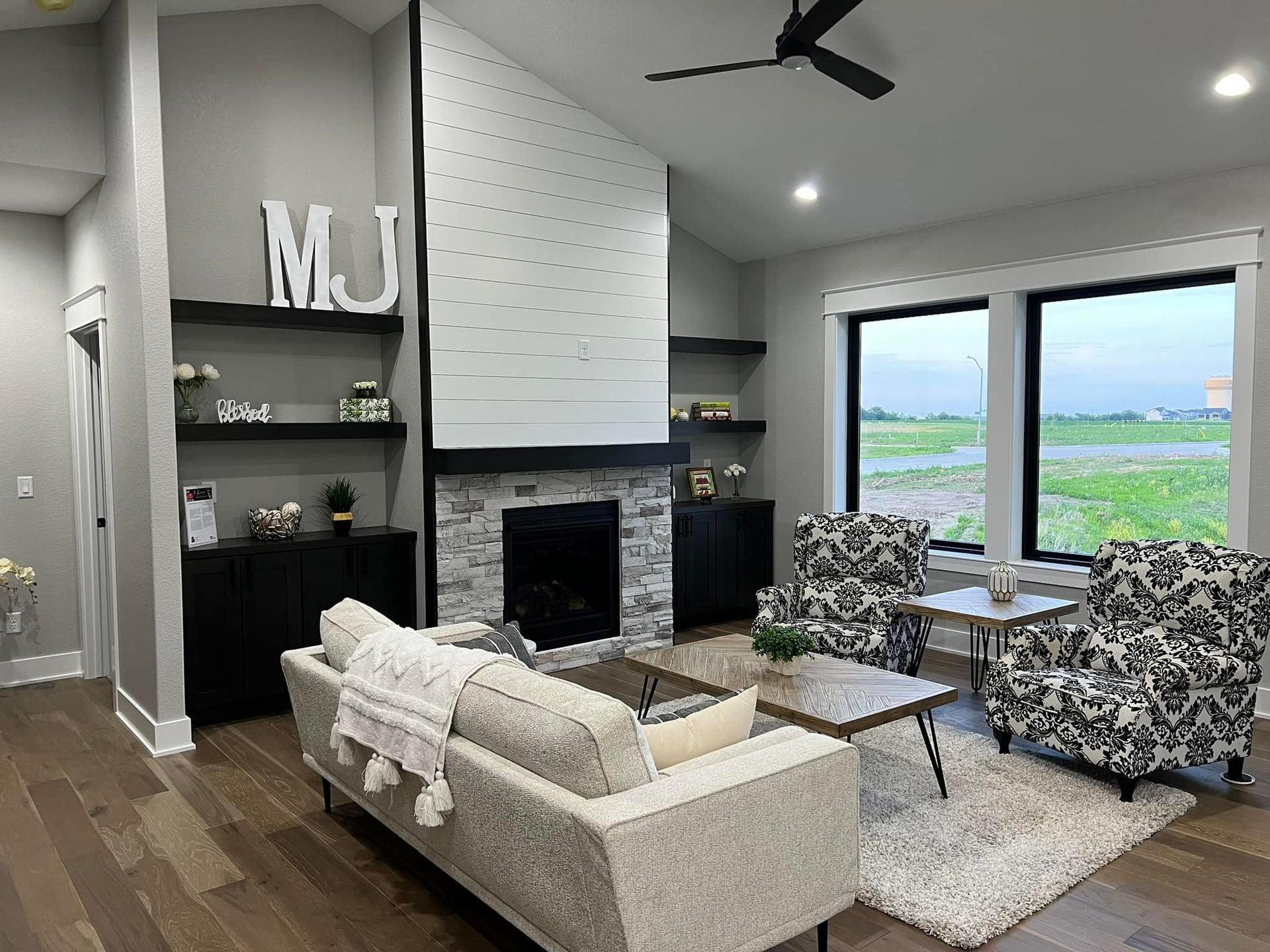 A living room with a couch , chairs , a fireplace and a ceiling fan.