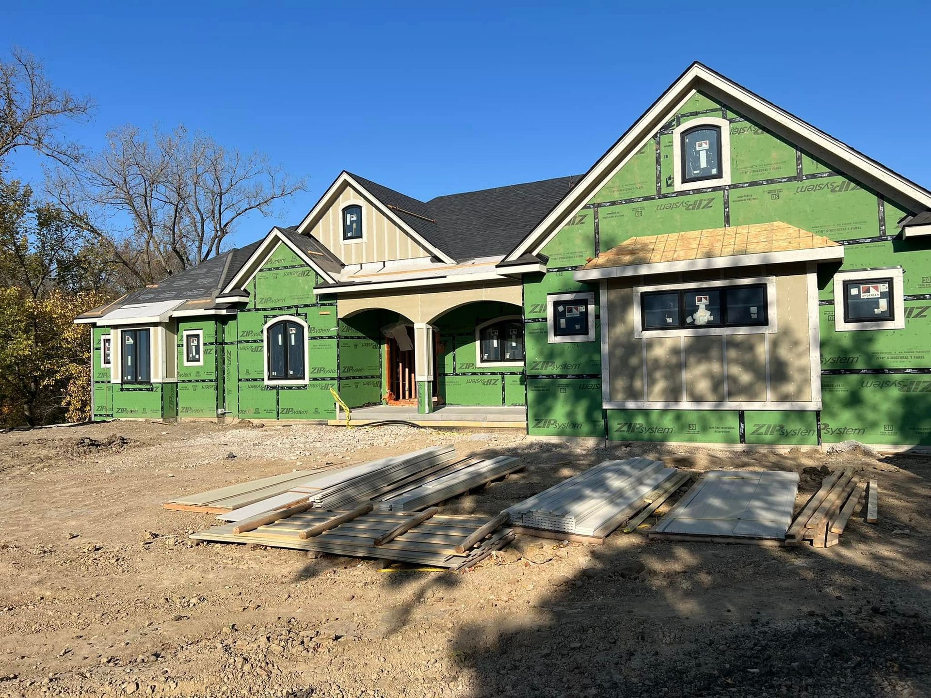 A large house is being built with green siding.