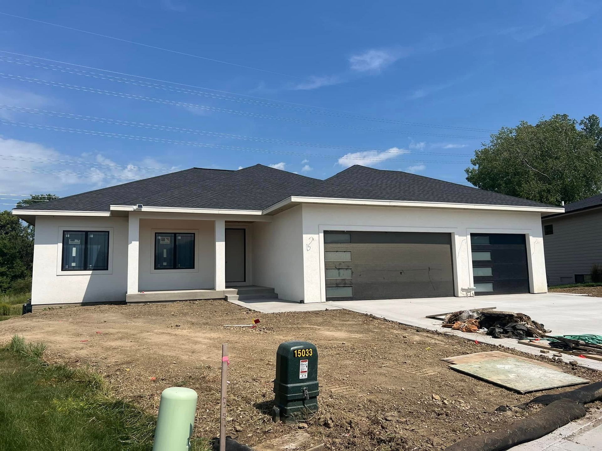 A white house with a black roof is being built.