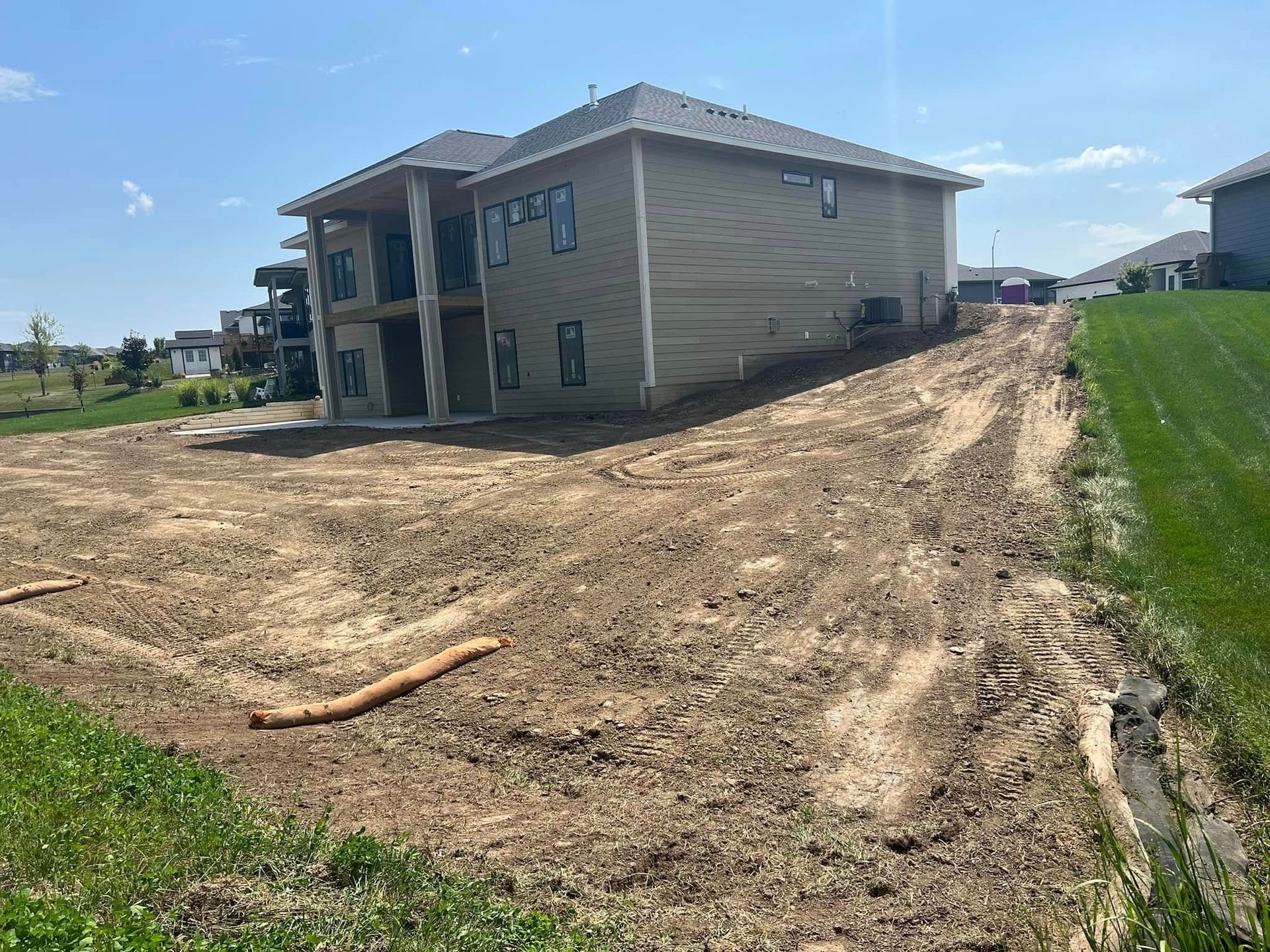A large house is sitting on top of a dirt hill.