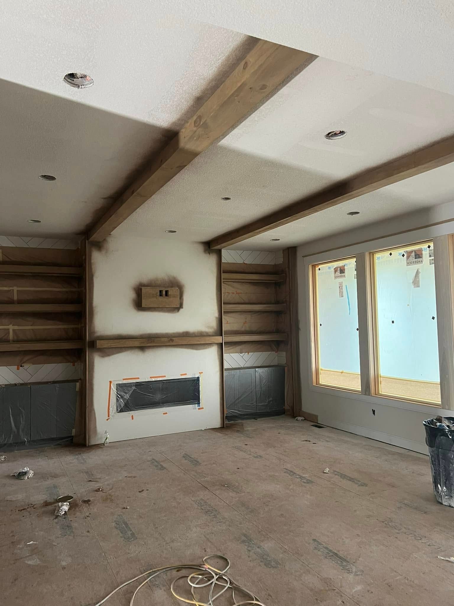 A living room under construction with a fireplace and shelves.