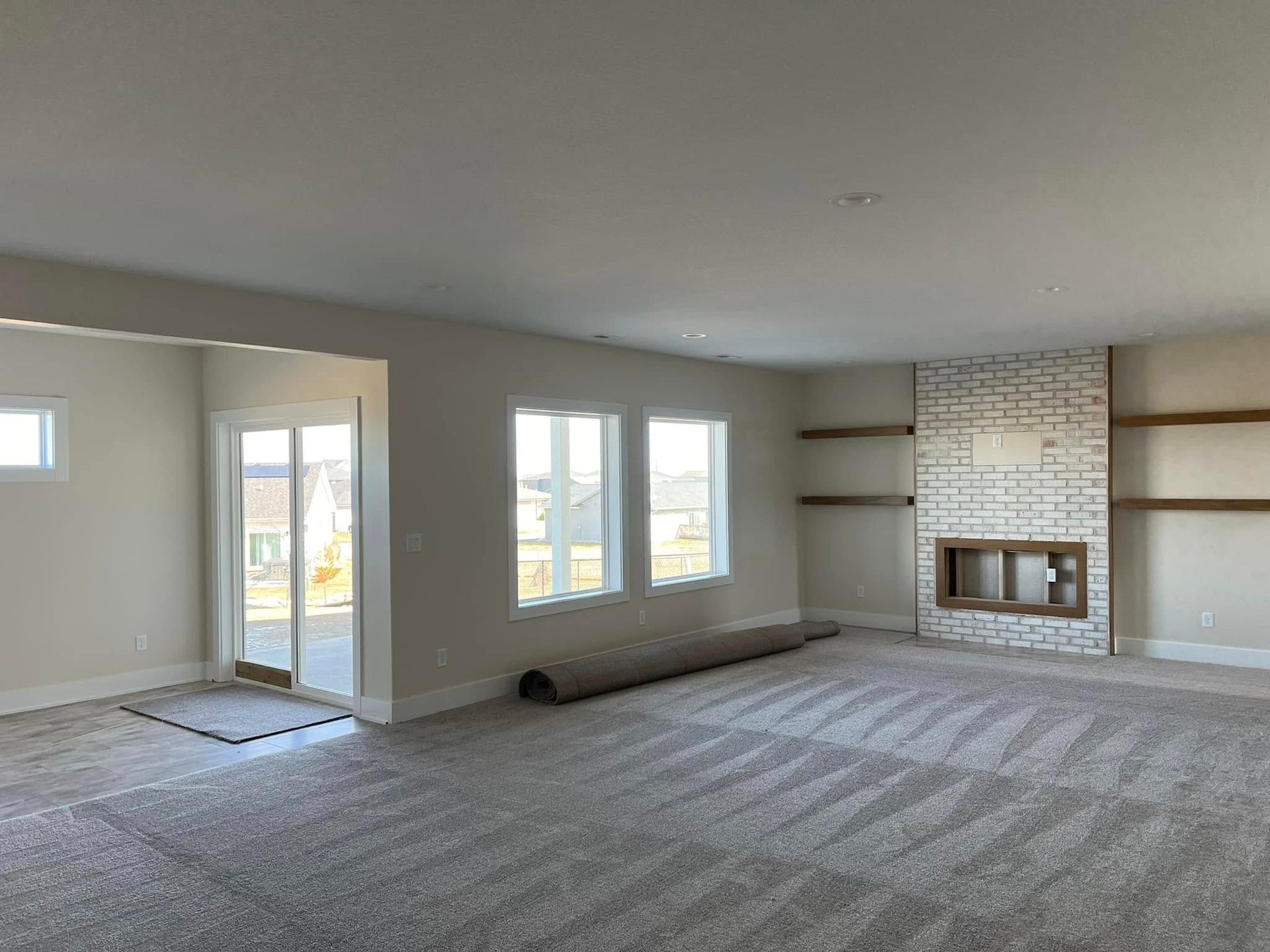 An empty living room with a fireplace and sliding glass doors.