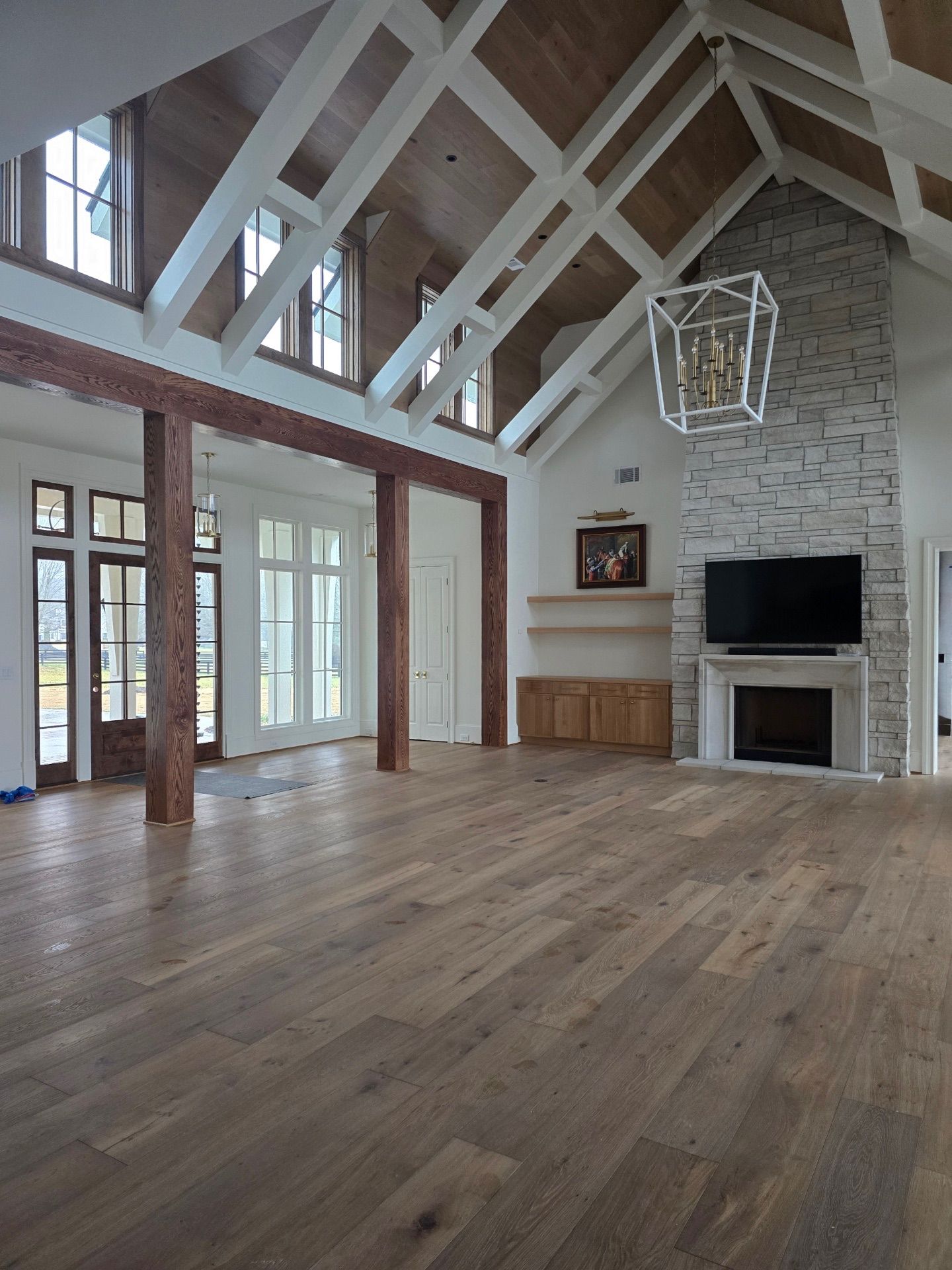 Spacious interior with wood flooring, vaulted ceiling, stone fireplace, and large windows.