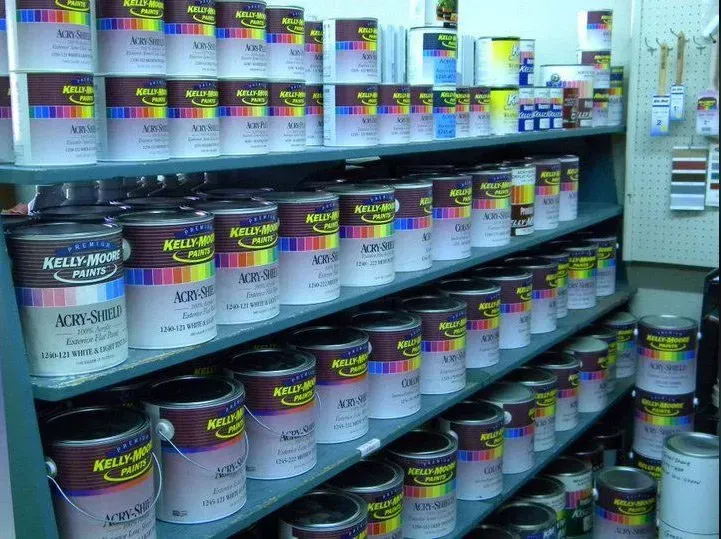 Shelves stocked with numerous cans of Kelly-Moore paint in a store setting.