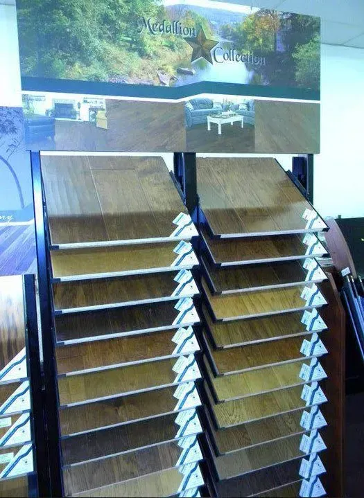 Display of various wood flooring samples on a stand with a branded header.