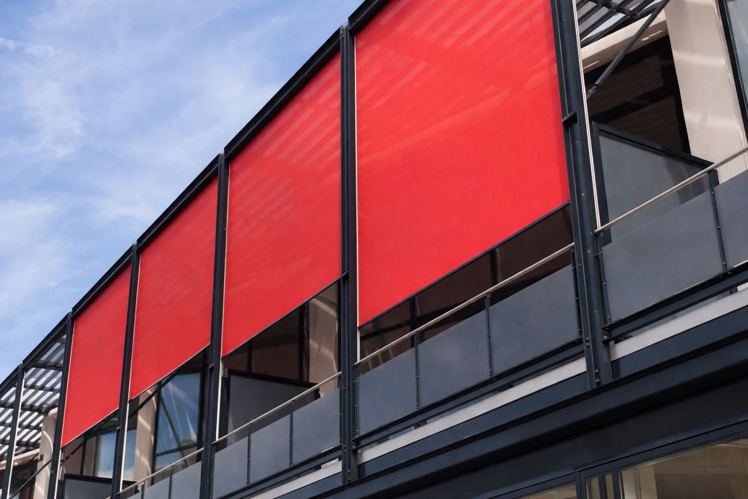 Tende rosse su un edificio moderno, che forniscono ombra dal sole.
