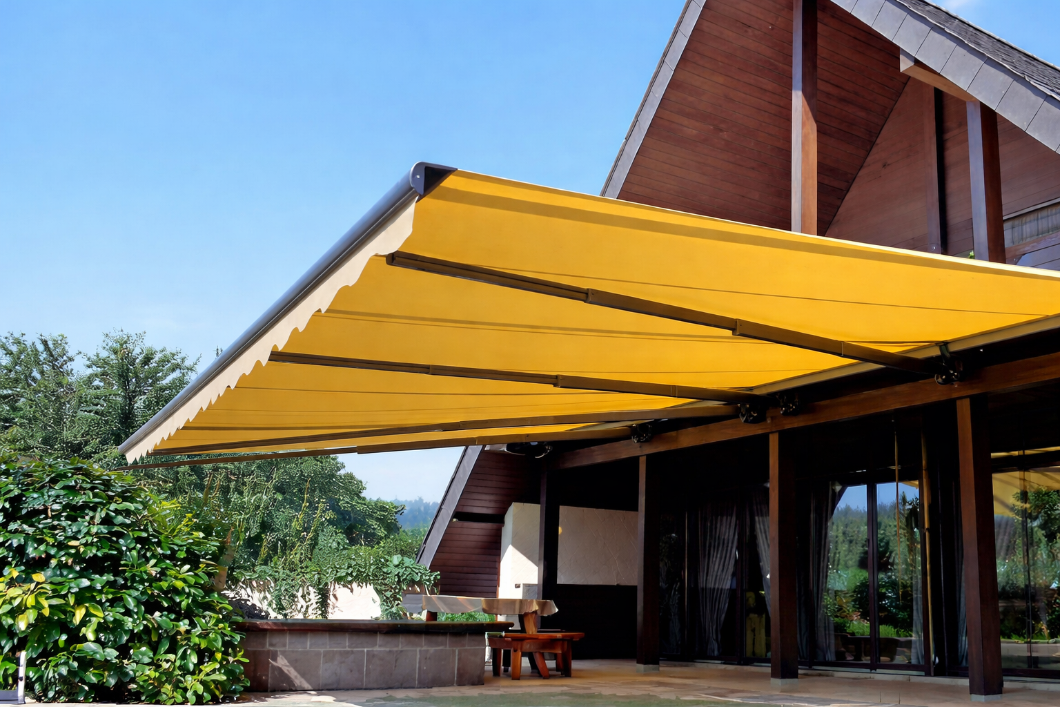 Tenda da sole retrattile gialla che si estende dalla struttura in legno di un edificio, in un ambiente esterno soleggiato.