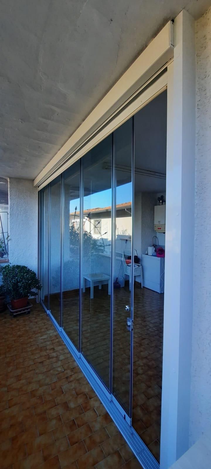 Porte scorrevoli in vetro su un balcone, con vista sulla stanza e sul cielo.