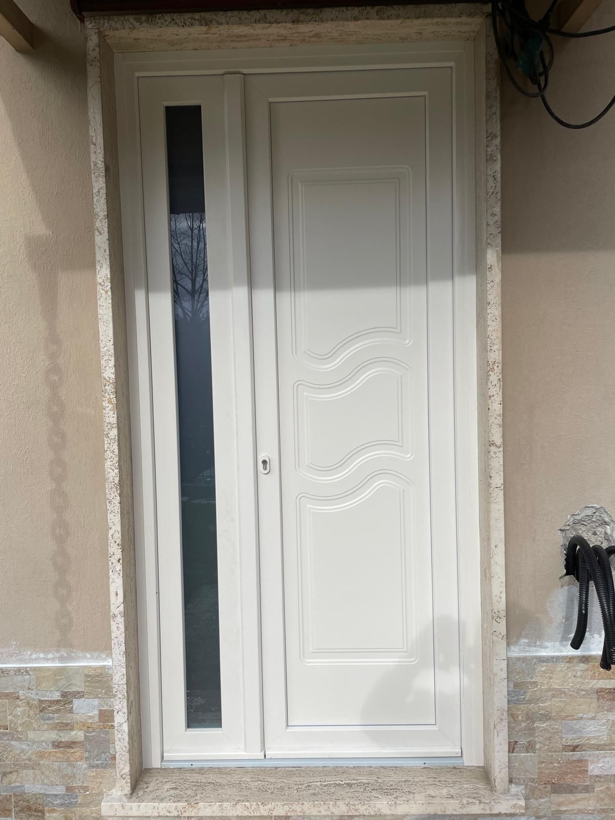 Porta d'ingresso bianca con design ondulato e pannello in vetro laterale.