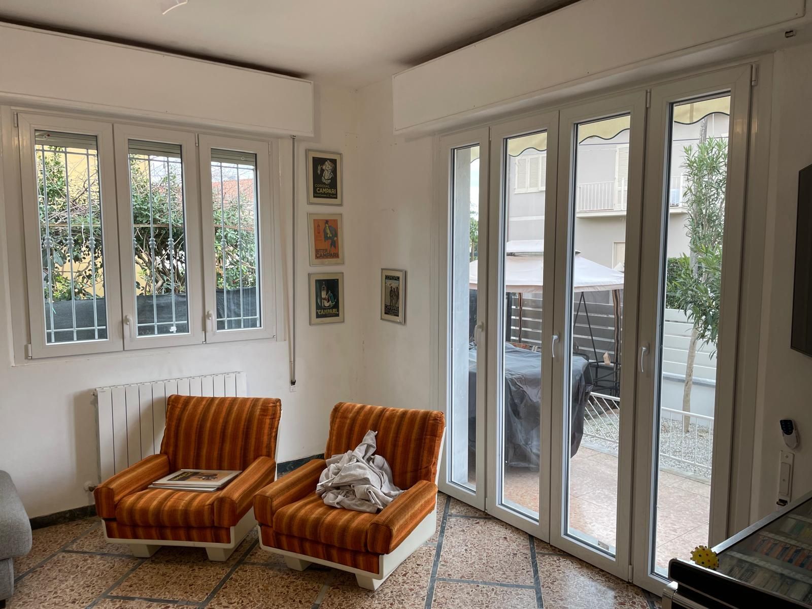 Due poltrone arancioni in una stanza con finestre e una porta scorrevole in vetro che si apre su un patio esterno.