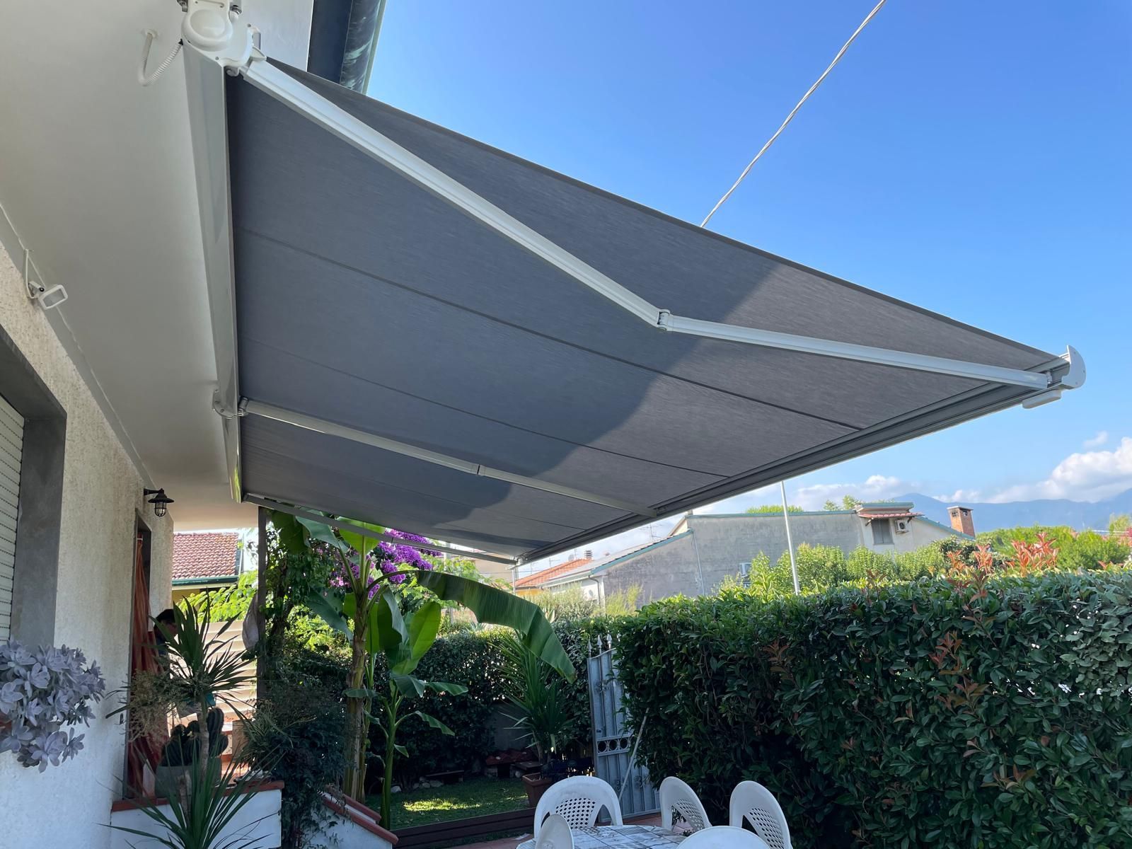 Tenda da sole retrattile grigia sopra un patio.