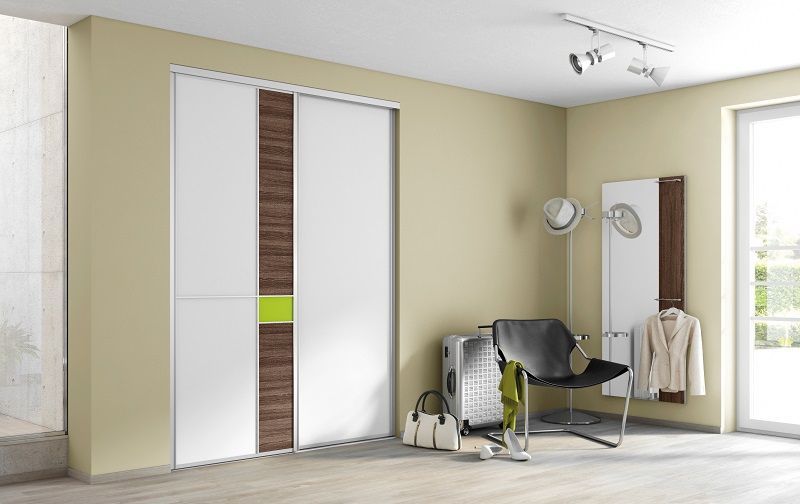 Porte scorrevoli bianche con dettagli in legno, una sedia, un bagaglio e uno specchio in un ingresso ben illuminato.