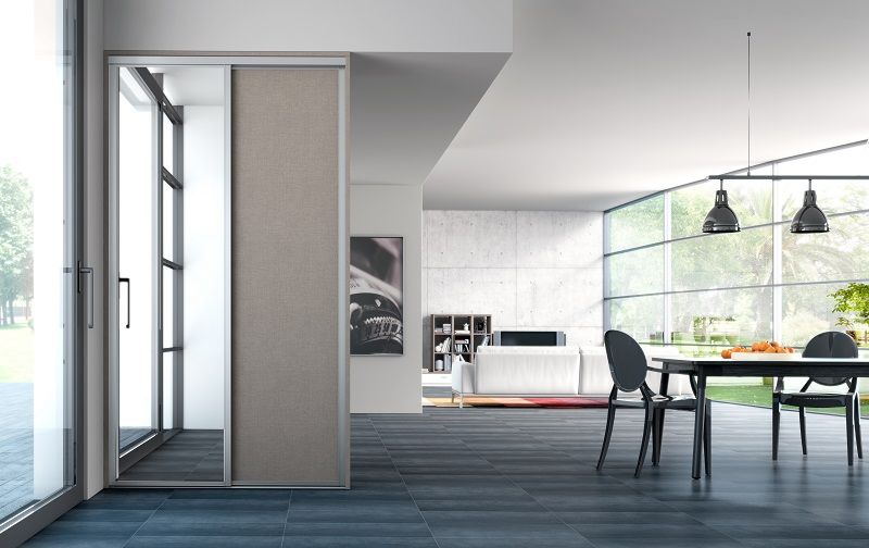Interni moderni con porta scorrevole, tavolo da pranzo e ampie finestre.