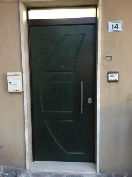 Porta verde scuro con maniglia e serratura argentate, numero 14 sul muro, cassetta della posta.