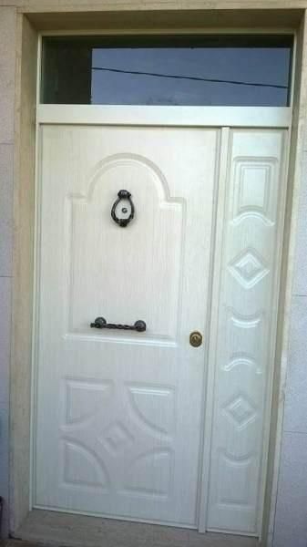 Porta d'ingresso bianca con finestra in alto, batacchio e maniglia neri.