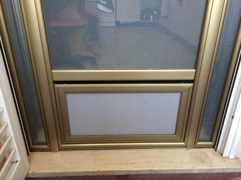 Porta a zanzariera con cornice dorata, una finestra più piccola con zanzariera 