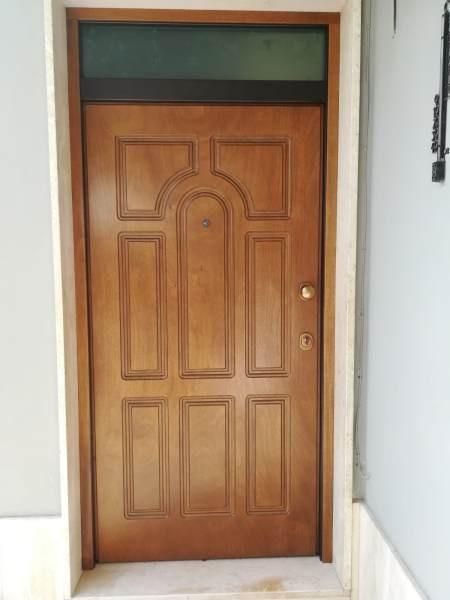 Porta d'ingresso in legno con sopraluce in vetro.