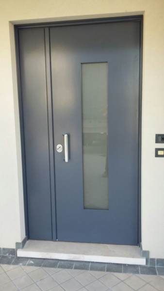 Porta moderna grigia con un lungo pannello in vetro e maniglia argentata.