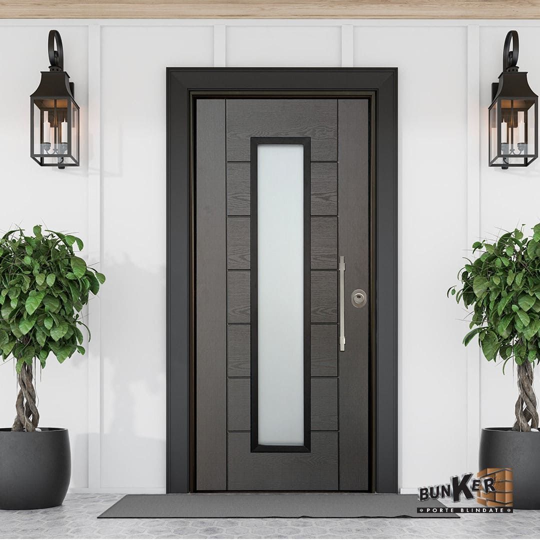Porta d'ingresso grigio scuro con pannello rettangolare in vetro smerigliato, fiancheggiata da piante e lanterne.