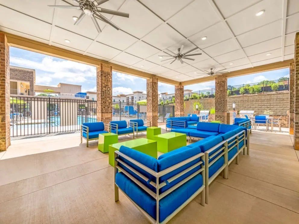 Outdoor lounge area with blue furniture overlooking a pool. Our Wexhaw, NC apartments provide the best in luxury living in downtown Waxhaw. Ready to make our community your home? Contact Waxhaw Mills today to learn more and schedule your personalized tour!