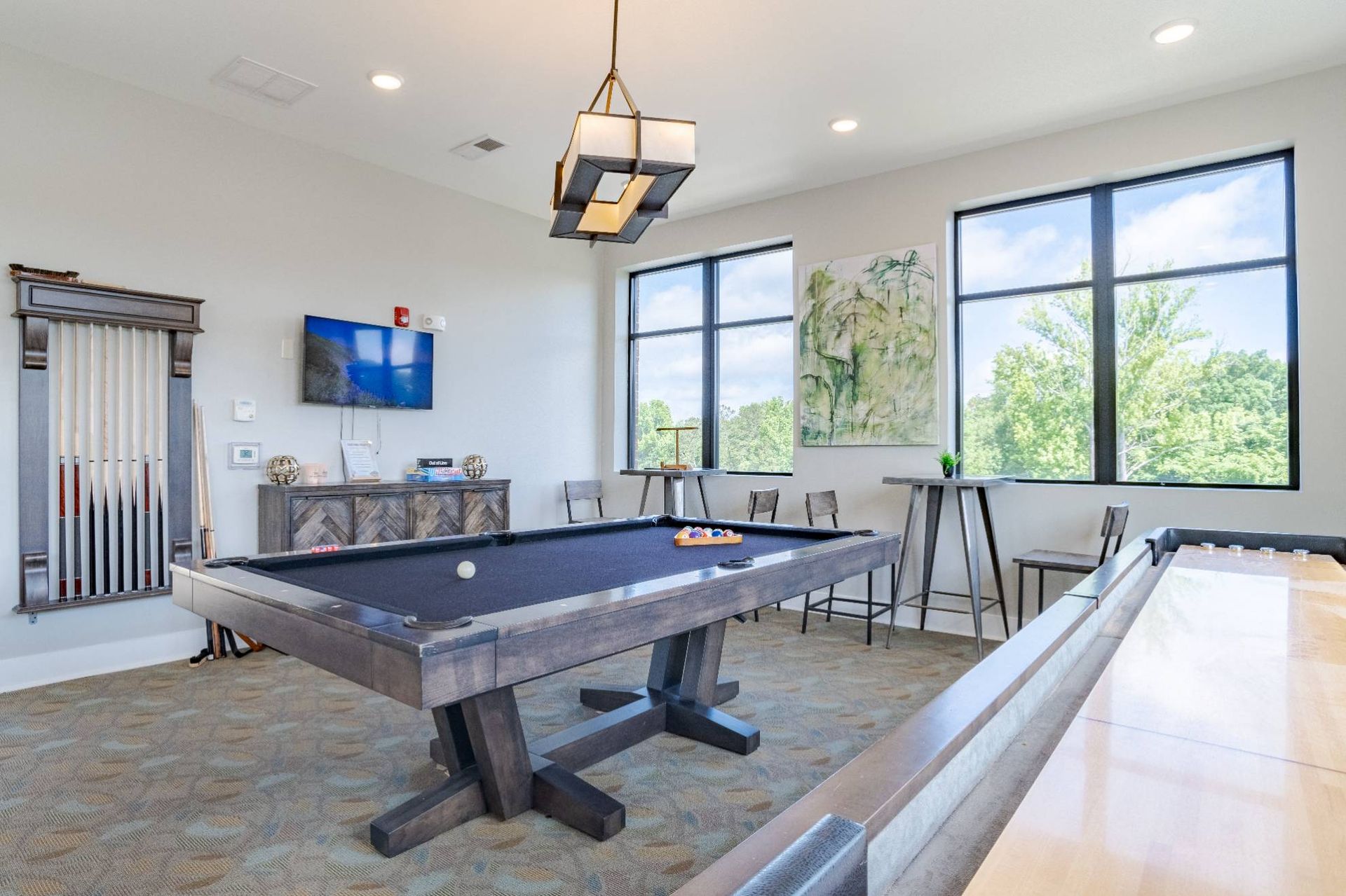 Interior community game room with a billiards table, high-top tables, and a wall TV. At Waxhaw Mills, our apartments for rent in Waxhaw, NC offer the best in service and enviable amenities. Experience all our community has to offer. Contact us to set up a tour!