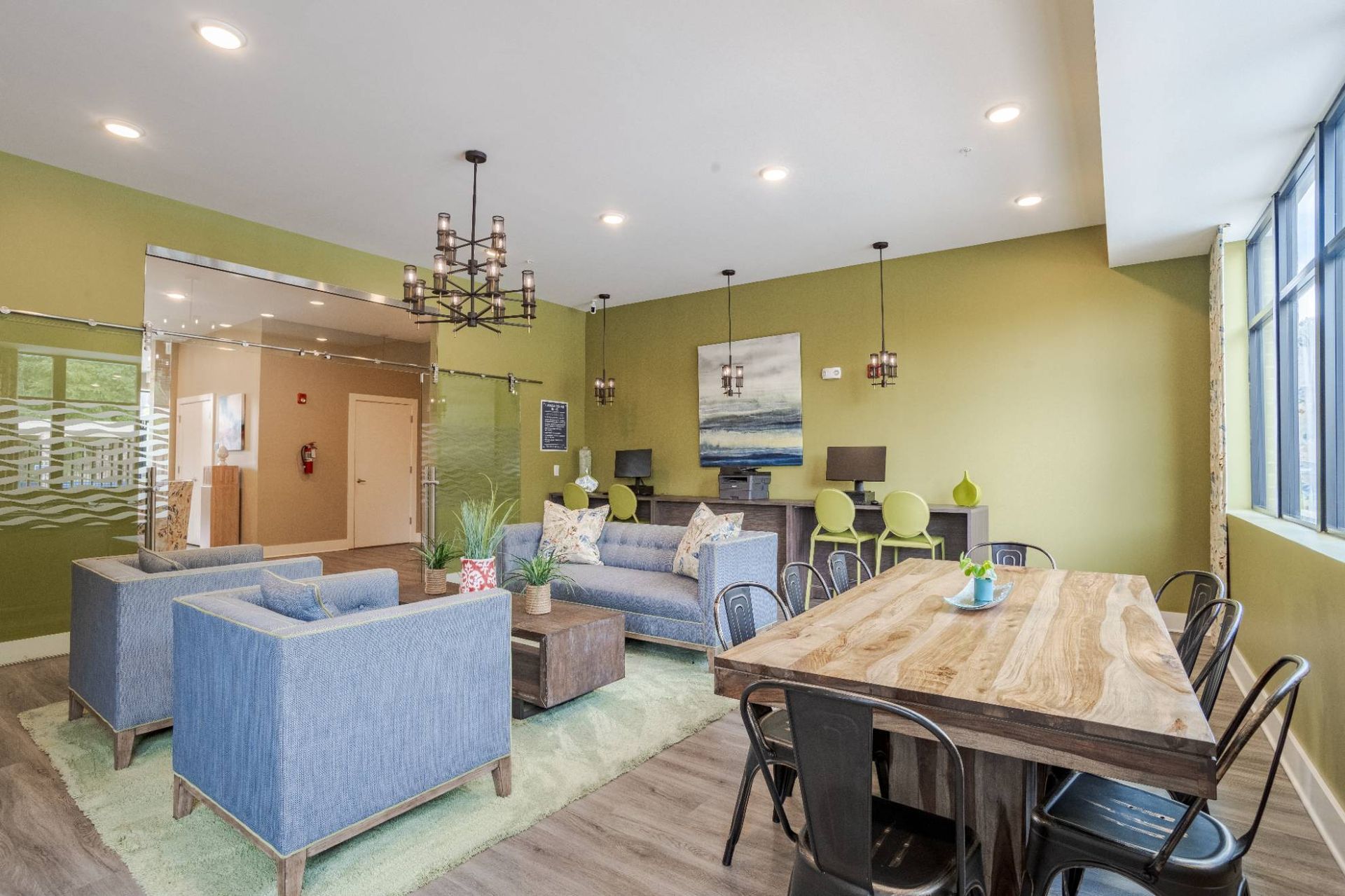 Interior of a community lounge with blue seating, a large wooden table, and green walls. At Waxhaw Mills, our apartments for rent in Waxhaw, NC offer the best in service and enviable amenities. Experience all our community has to offer. Contact us to set up a tour!